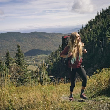 Female hiker walking on a grassy trail at Mount Mansfield.