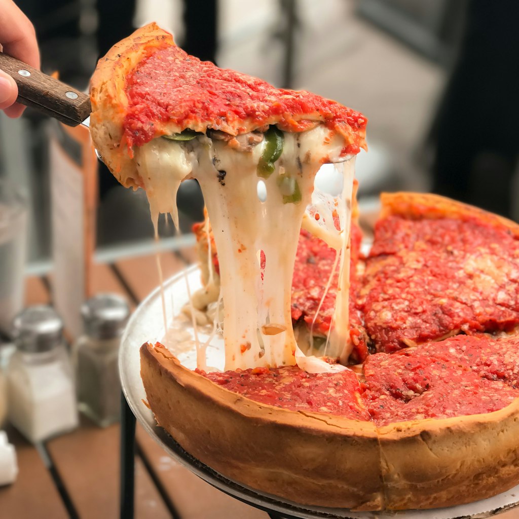 Taking a slice of Chicago-style deep dish cheese pizza with tomato sauce.