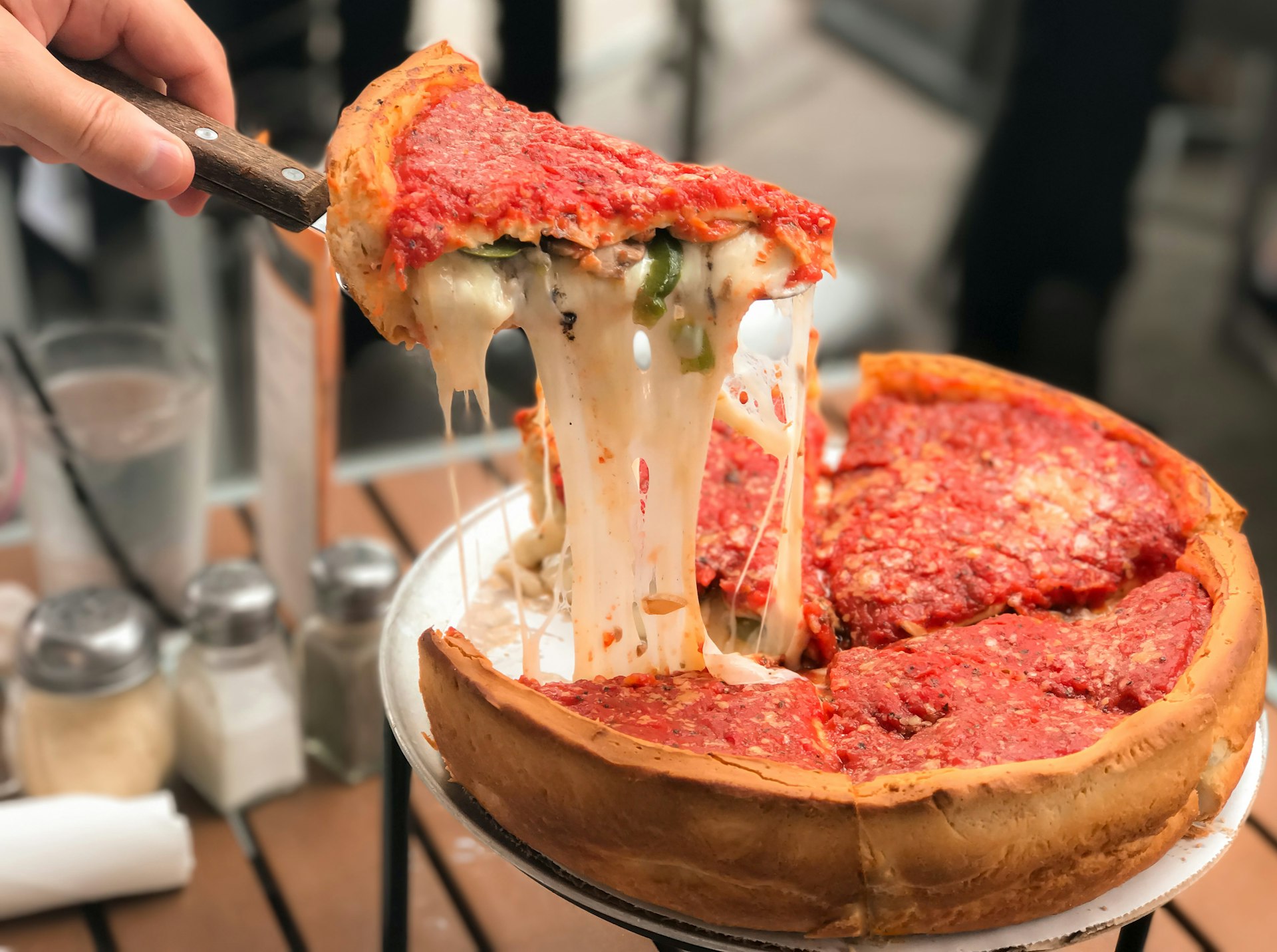 Pulling up a slice of Chicago-style deep dish cheese pizza with tomato sauce. 