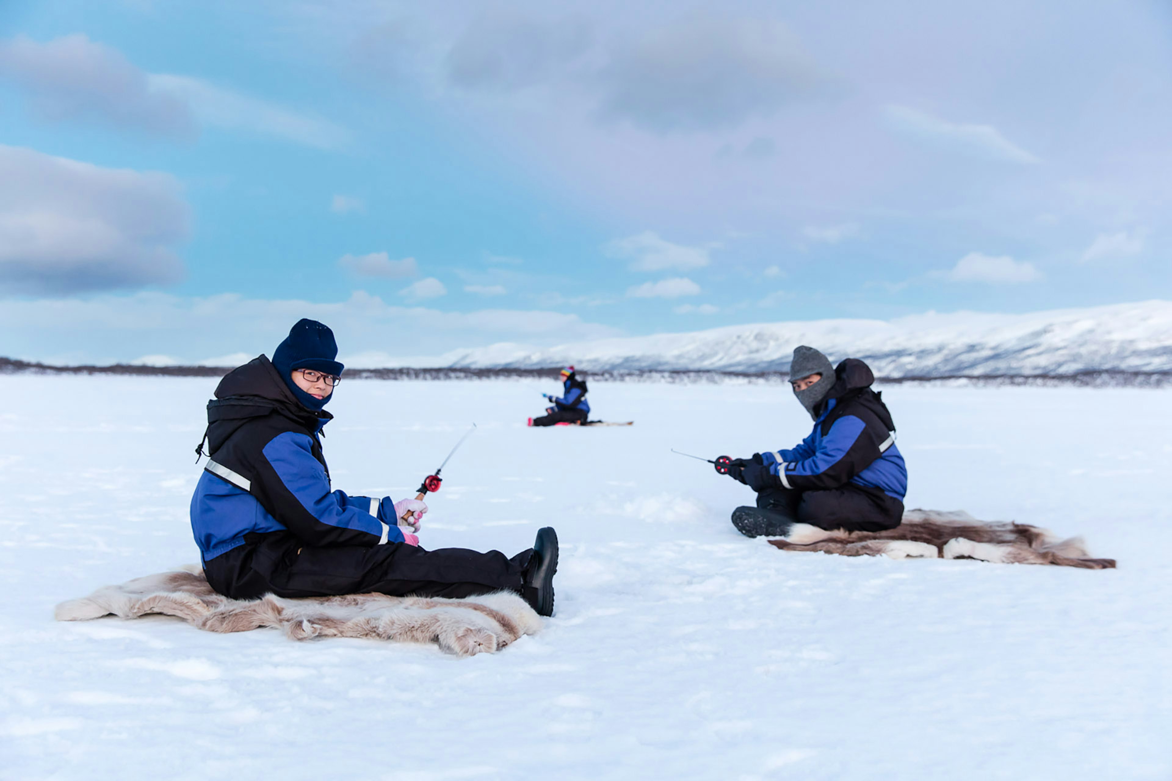 People sitting on ice going ice fishing