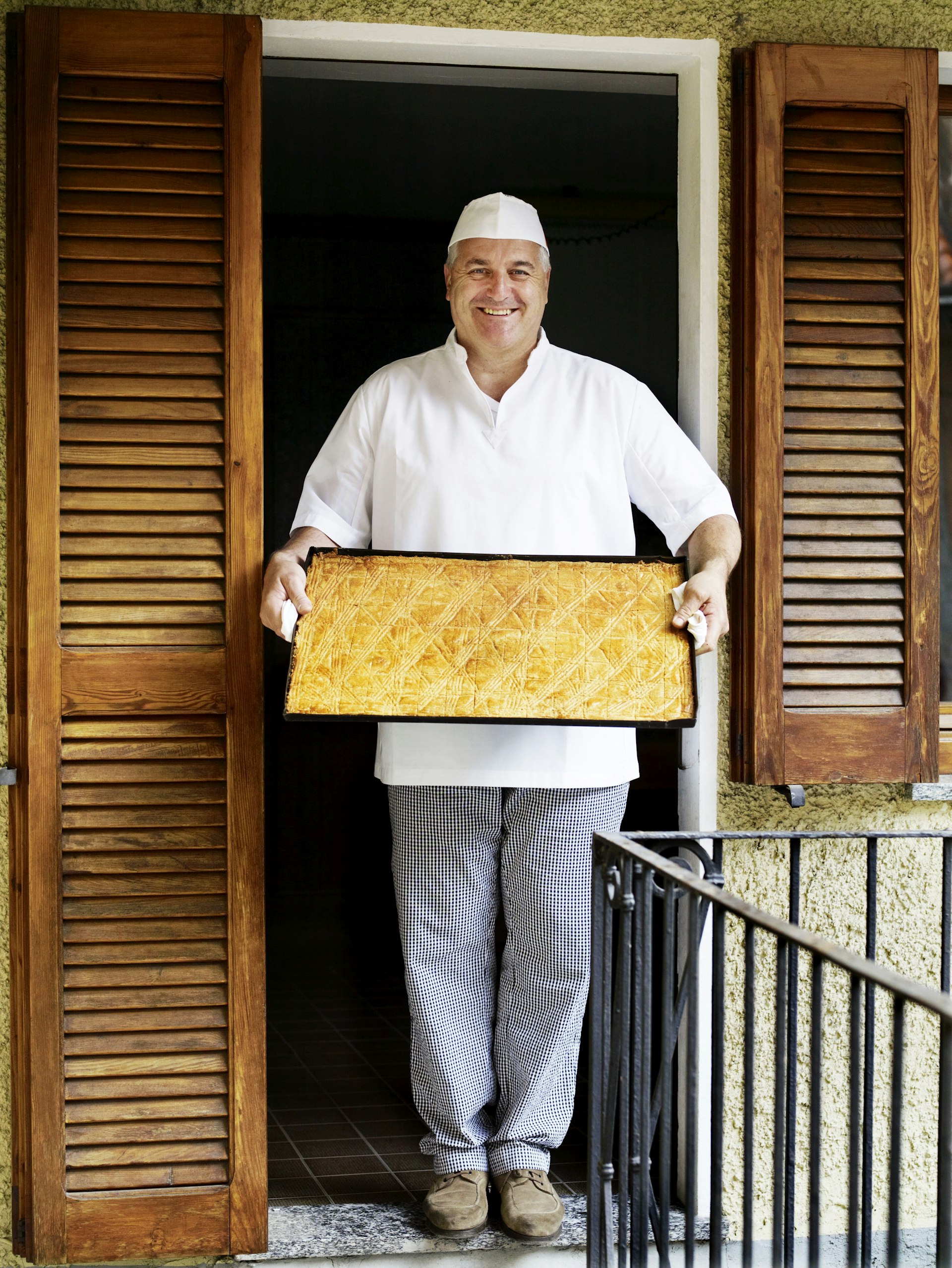 Baker holding a tray of fugascina biscuits at Al Vecchio Fornaio Pasticcere in Mergozzo.