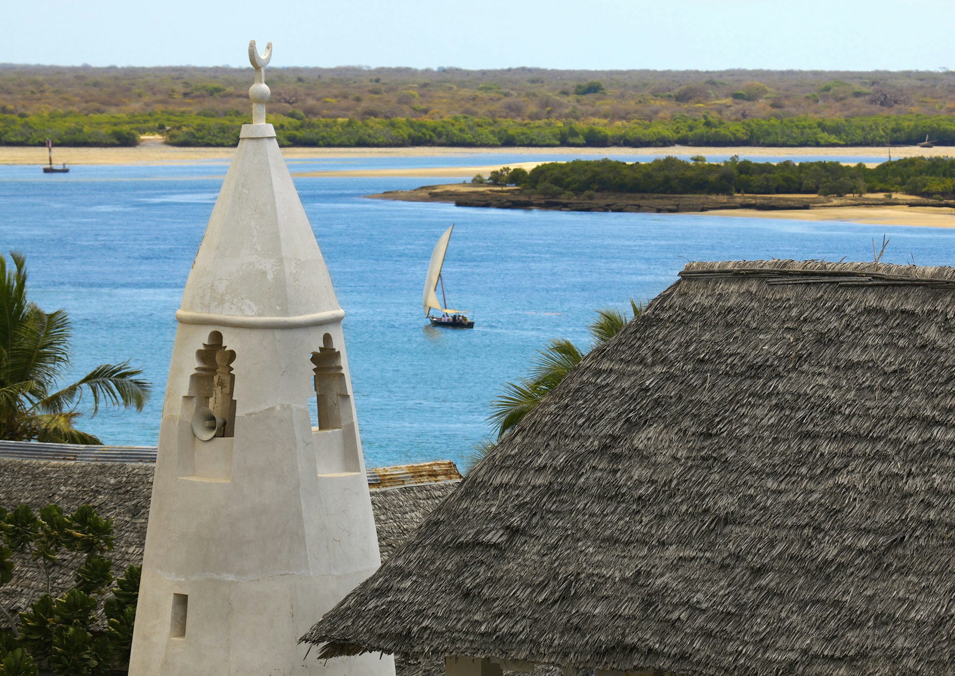 A minaret shapes the skyline of Lamu, with a blue sea 