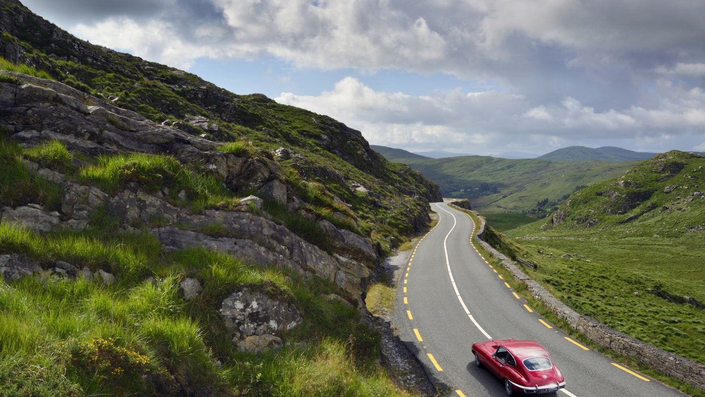E-Type Jaguar driving on country road between Kenmare and Killarney.