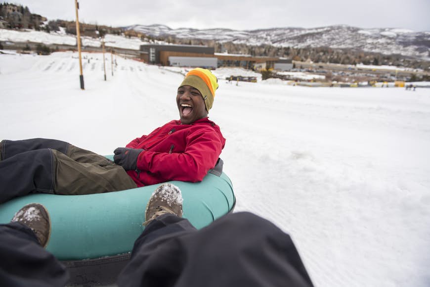 A man laughing while snow tubing
