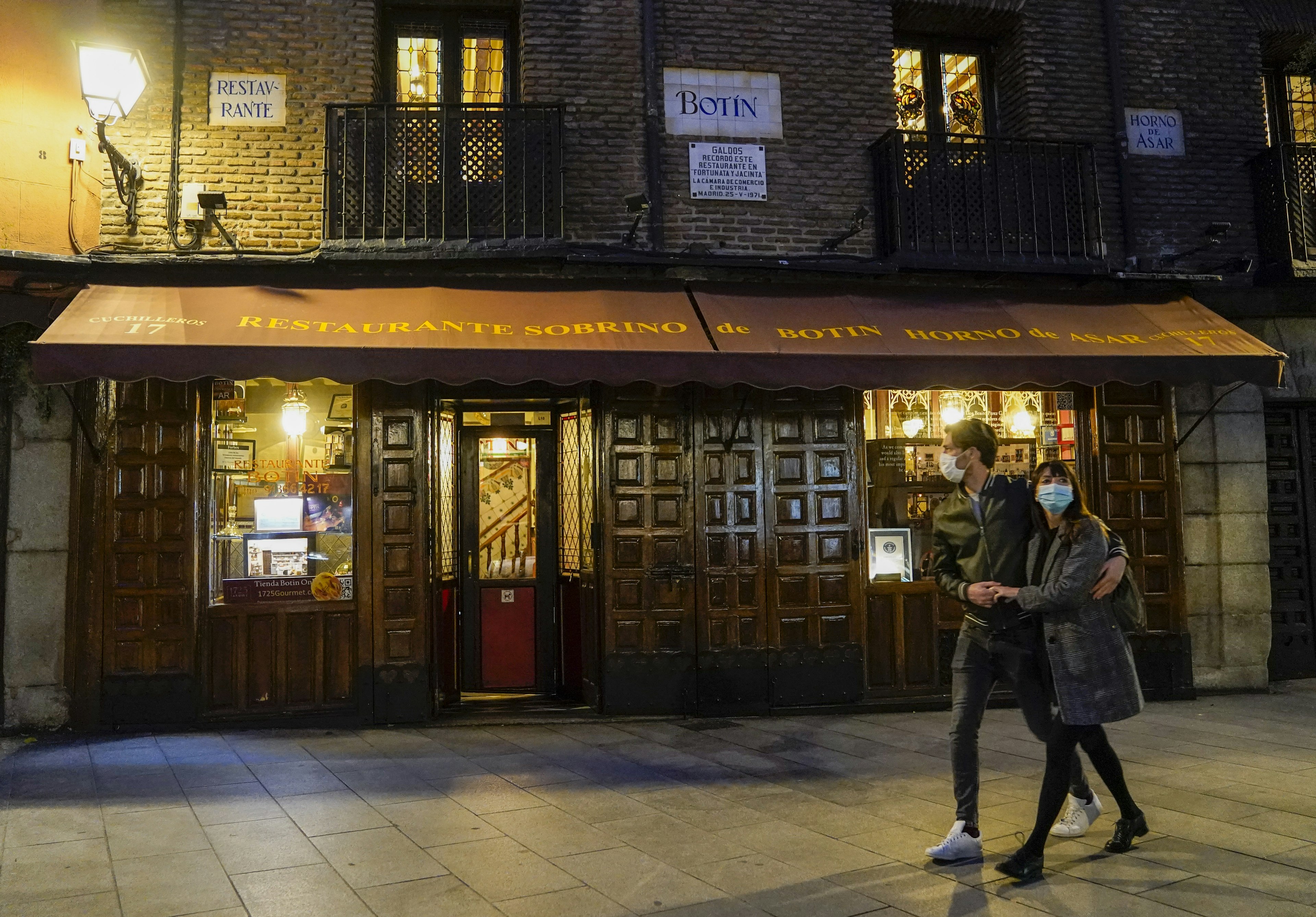 Pedestrians wearing protective masks walk past Botin restaurant in Madrid, Spain,