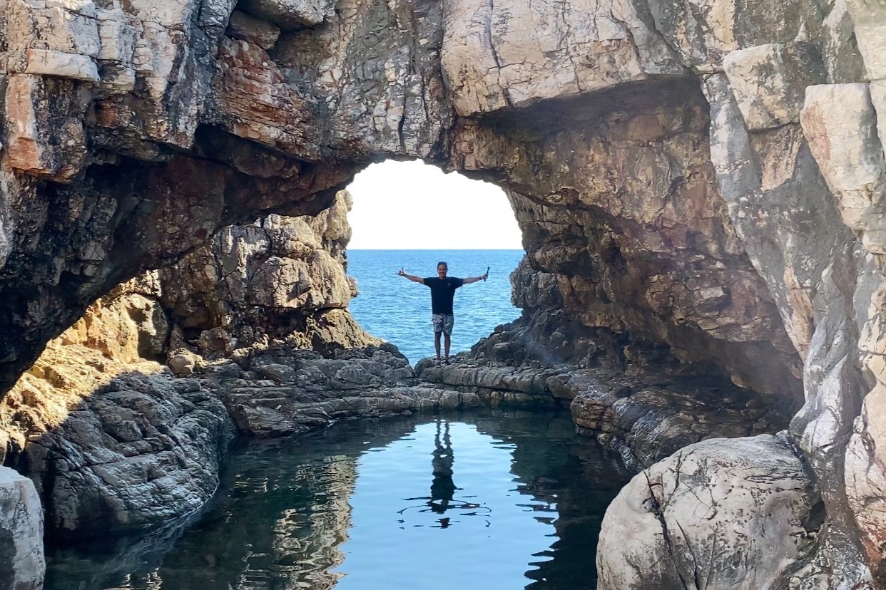 A man standing in front of rocks on Lokrum Island in Croatia