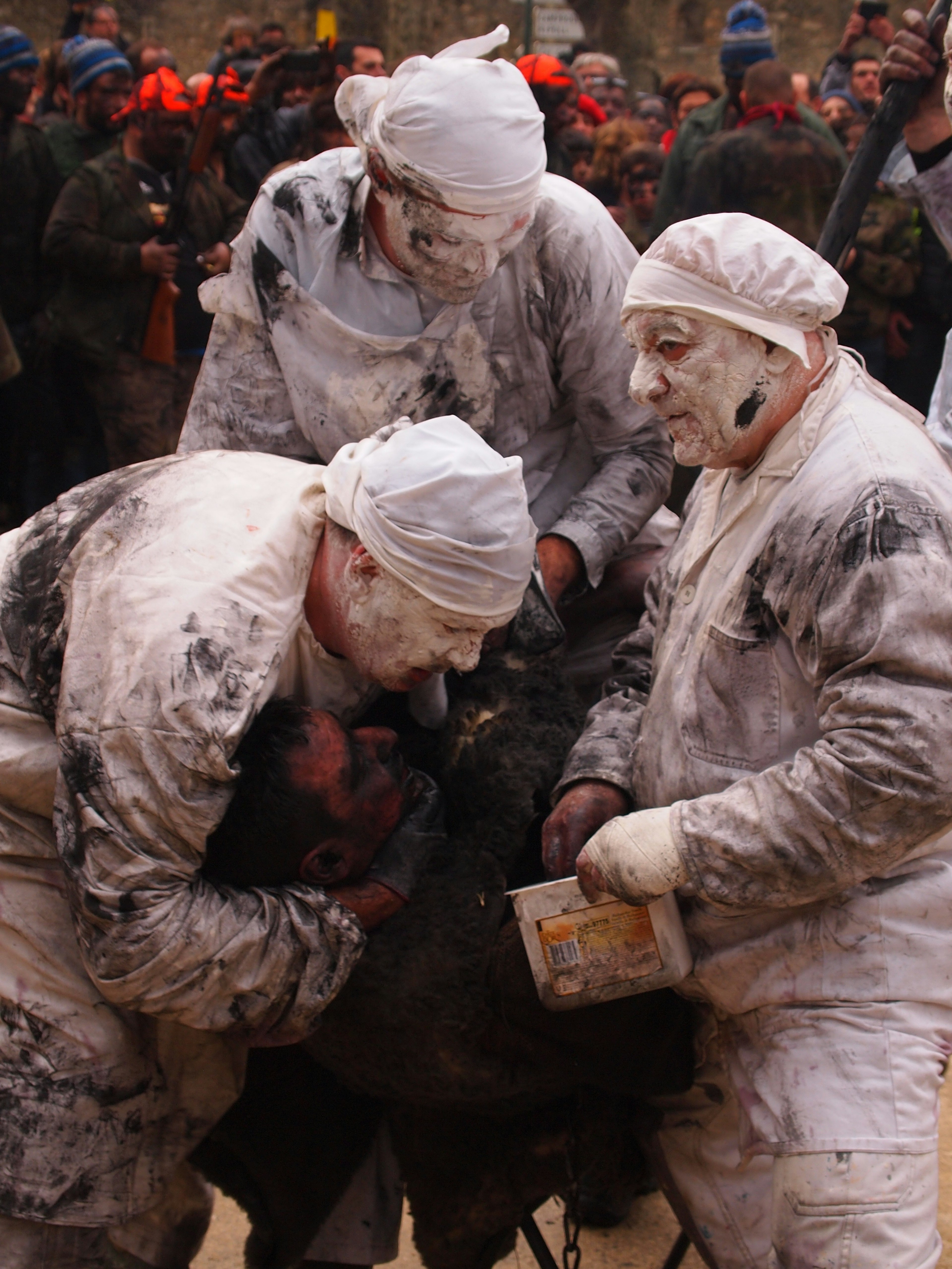 Three men dressed in white gather tightly round a single person dressed in black