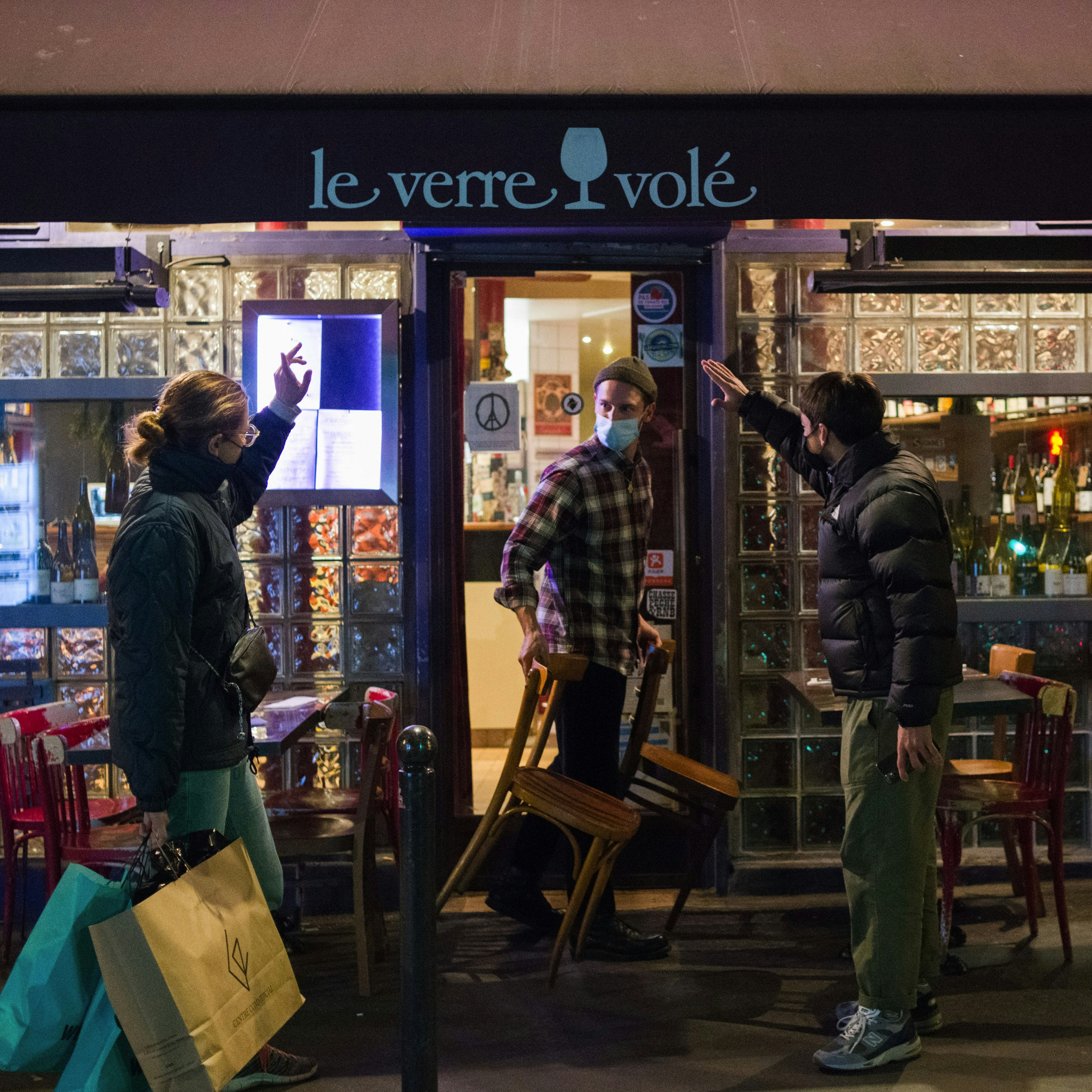 Customers wave goodbye to a waiter while leaving a bar ahead of a curfew in Paris, France, on Saturday, Oct. 17, 2020. President Emmanuel Macron will confine residents of nine of the country's biggest cities to their homes between 9 p.m. and 6 a.m. for four weeks starting on Saturday. Photographer: Nathan Laine/Bloomberg via Getty Images