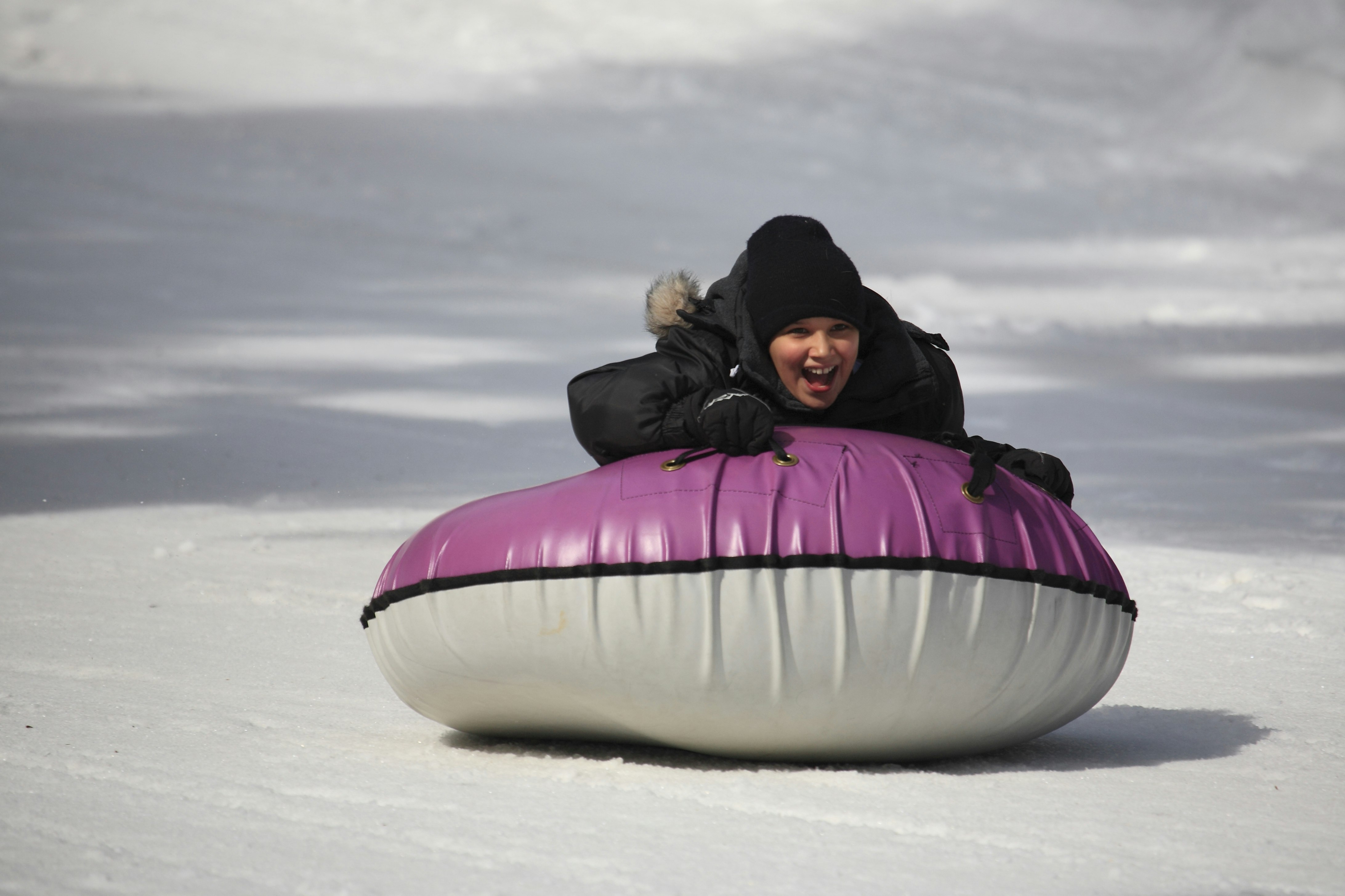 Girl on inner tube rides down a snow-packed slope