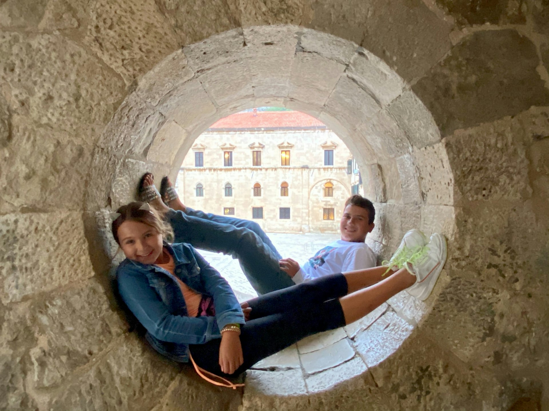 A young boy and girl sitting in a stone circular hollow in Dubrovnik