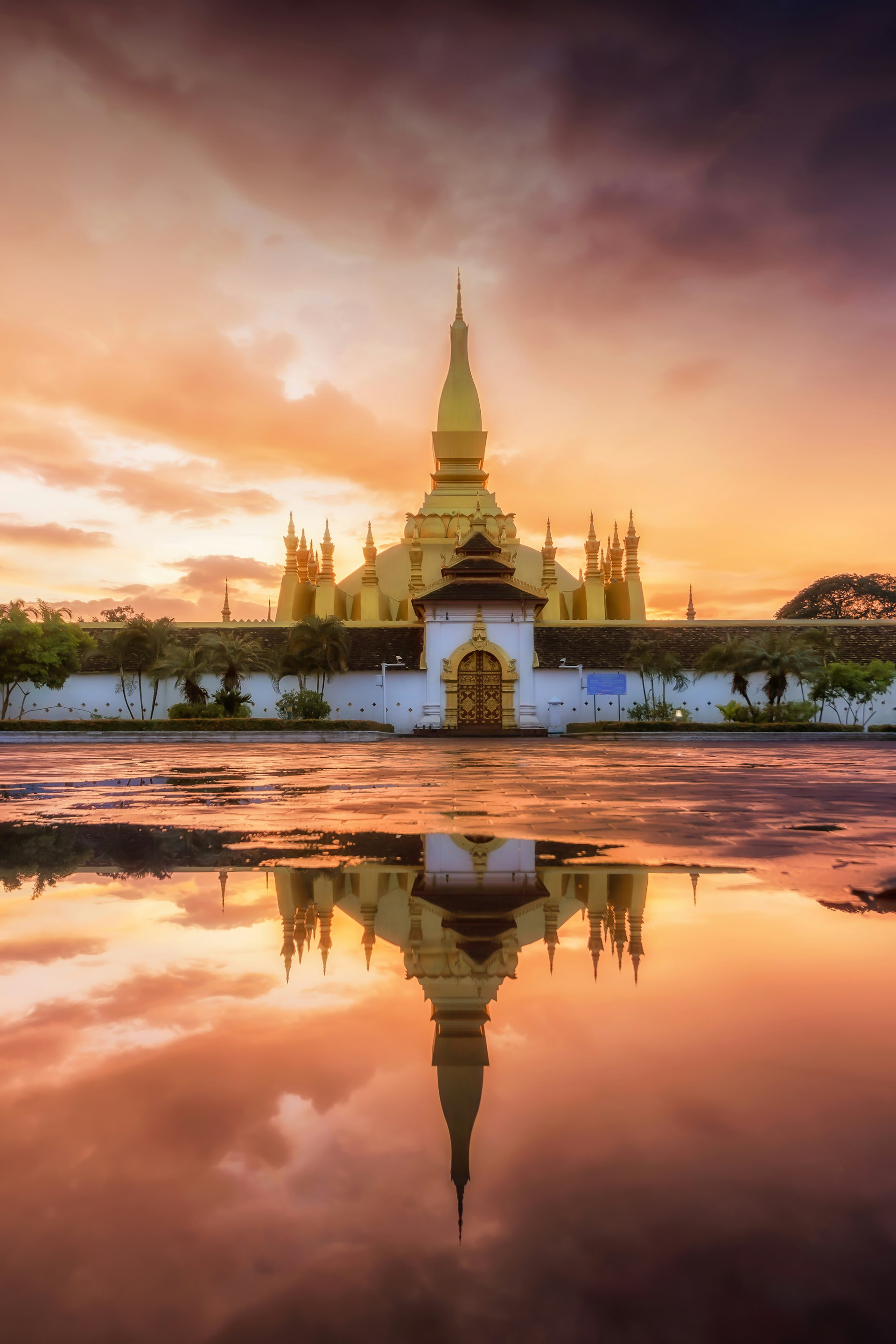 A gold temple building reflected in still water at dusk