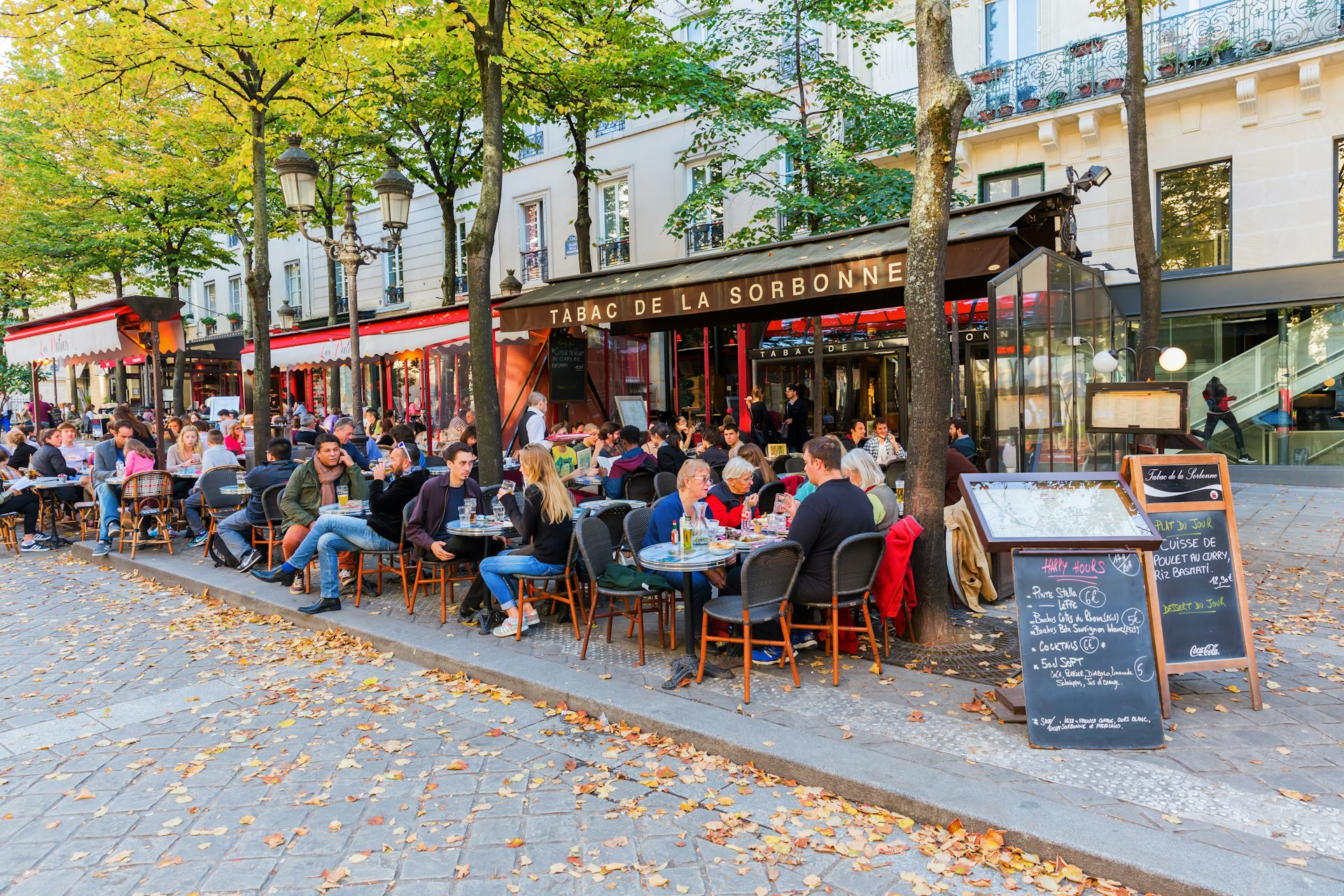 People sat at tables on a pavement outside a cafe