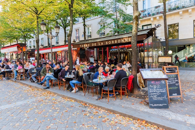 People sat at tables on a pavement outside a cafe