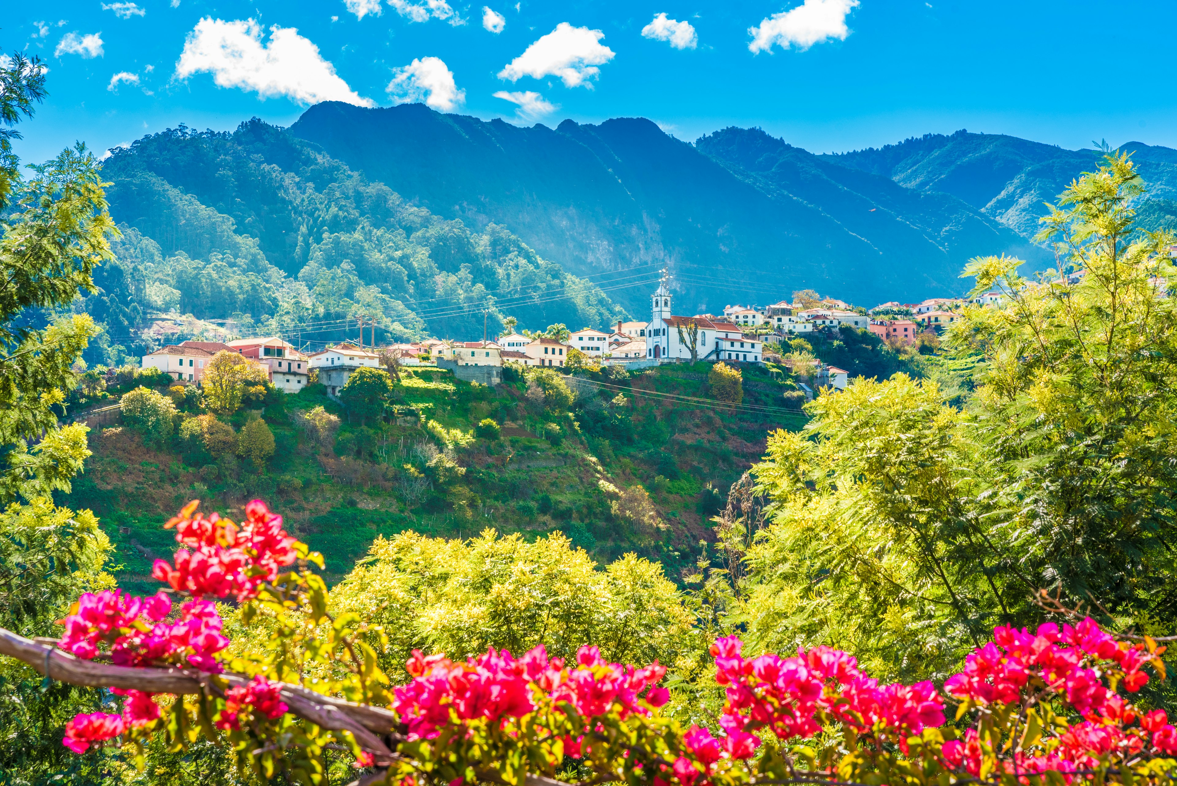 A valley with red-roofed houses lining the mountain ridge all bathed in sunshine