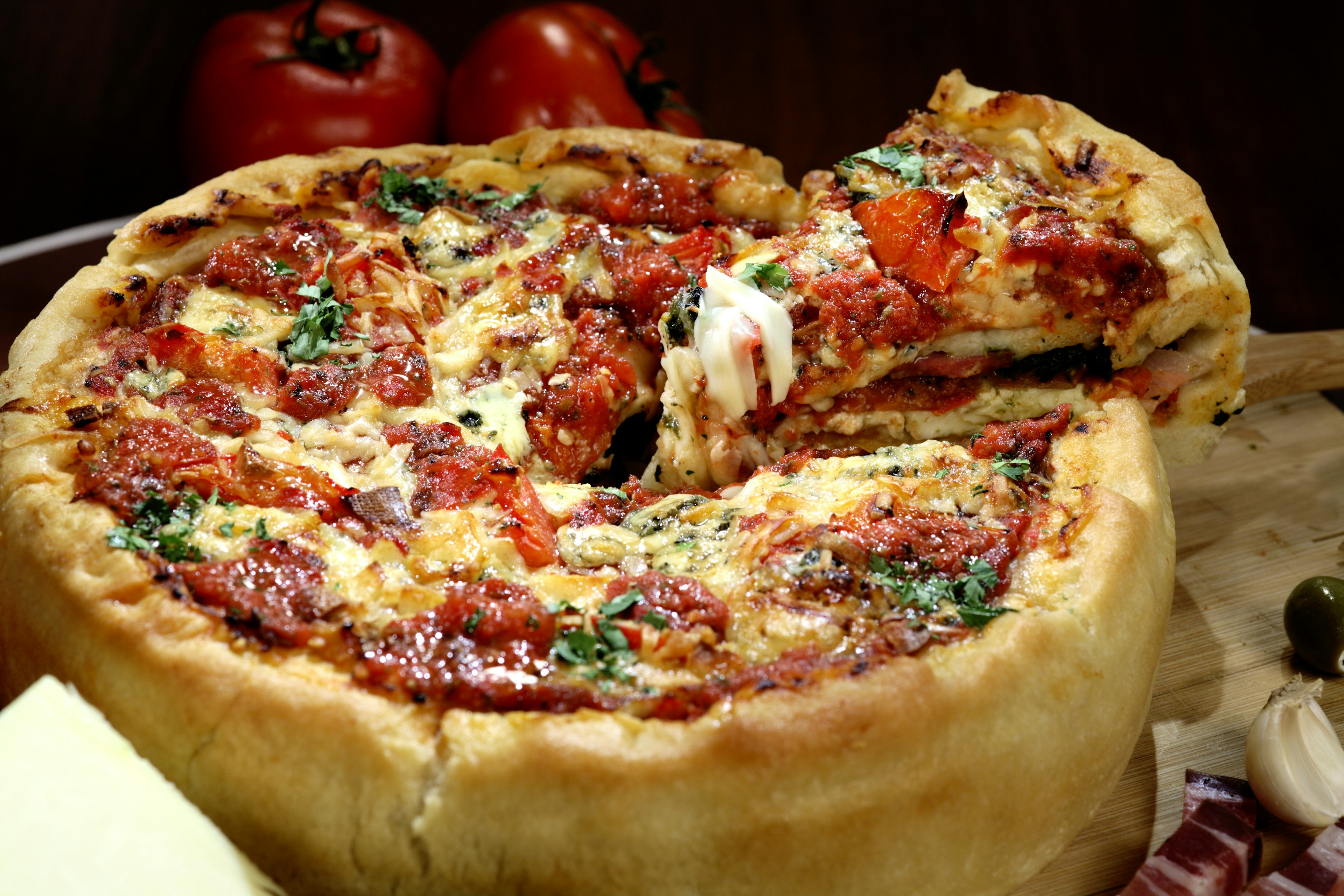 Chicago deep dish pizza loaded with an array of toppings sits on a table