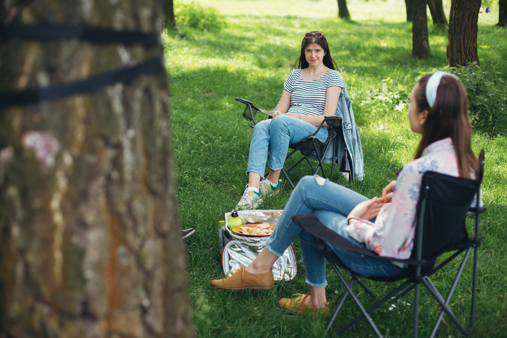 Small group of young woman enjoying conversation at picnic with social distance in summer park