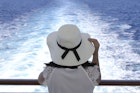 Woman with sun hat looking out to sea on a cruise ship