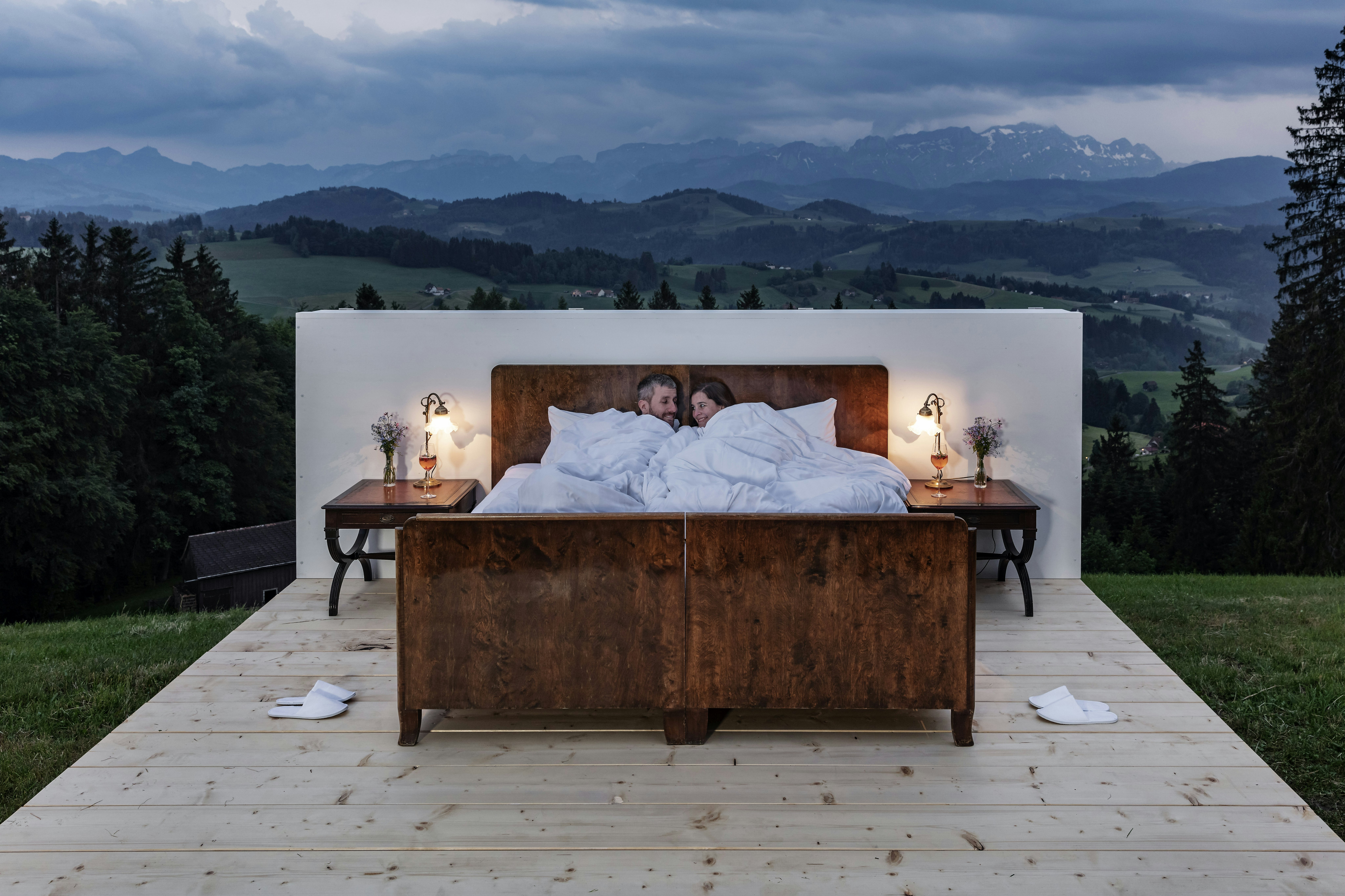 A couple lies in bed in a room without windows in the Swiss Alps