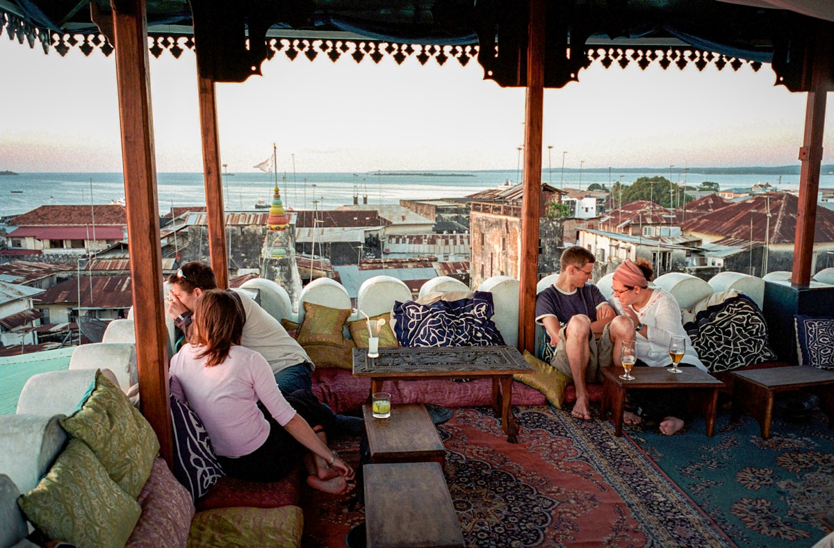 ZANZIBAR, TANZANIA - OCTOBER 6:  (.)  Tourists look towards the sunset while resting on a roof top restaurant at the Emerson & Green Hotel October 6, 2002 in Stone town in central Zanzibar, Tanzania. Zanzibar has become a popular tourist destination due to the beautiful virgin beaches and influence of Arabic, Indian and African cultures on the island.  (Photo by Per-Anders Pettersson/Getty Images)