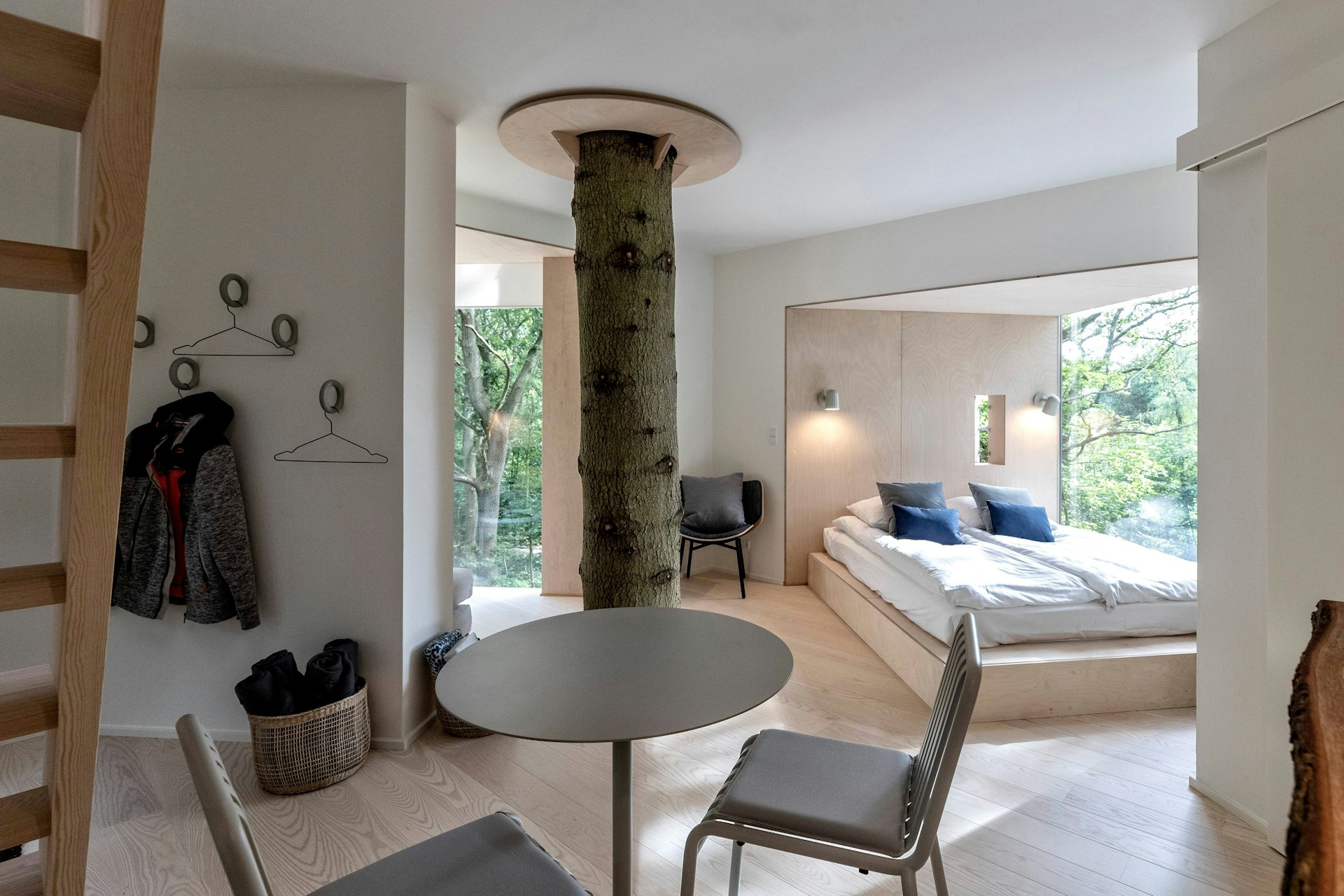 A smart interior of a treehouse, with a trunk going straight through the middle. 