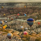 Colorful hot air balloons over rolling landscape.