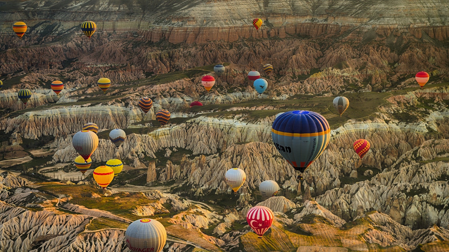 Colorful hot air balloons over rolling landscape.