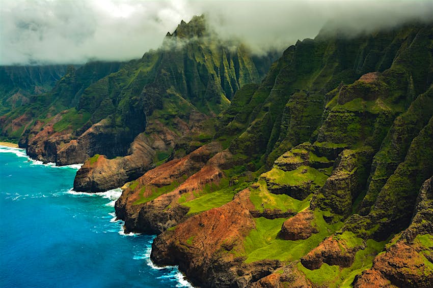 The rugged Na Pali Coast from a helicopter, with clouds overhead