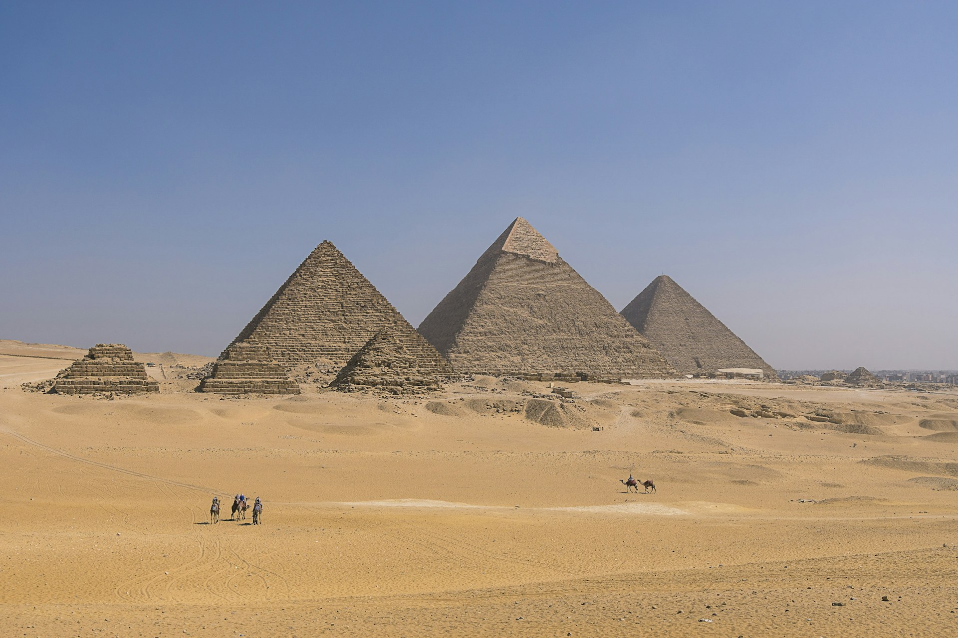 Kamelryttare på väg mot de tre stora pyramiderna i Giza (från vänster till höger: Menkaura, Khafra & Khufu).