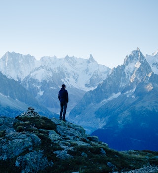 A hiker standing in the mountains above Chamonix in early morning light..