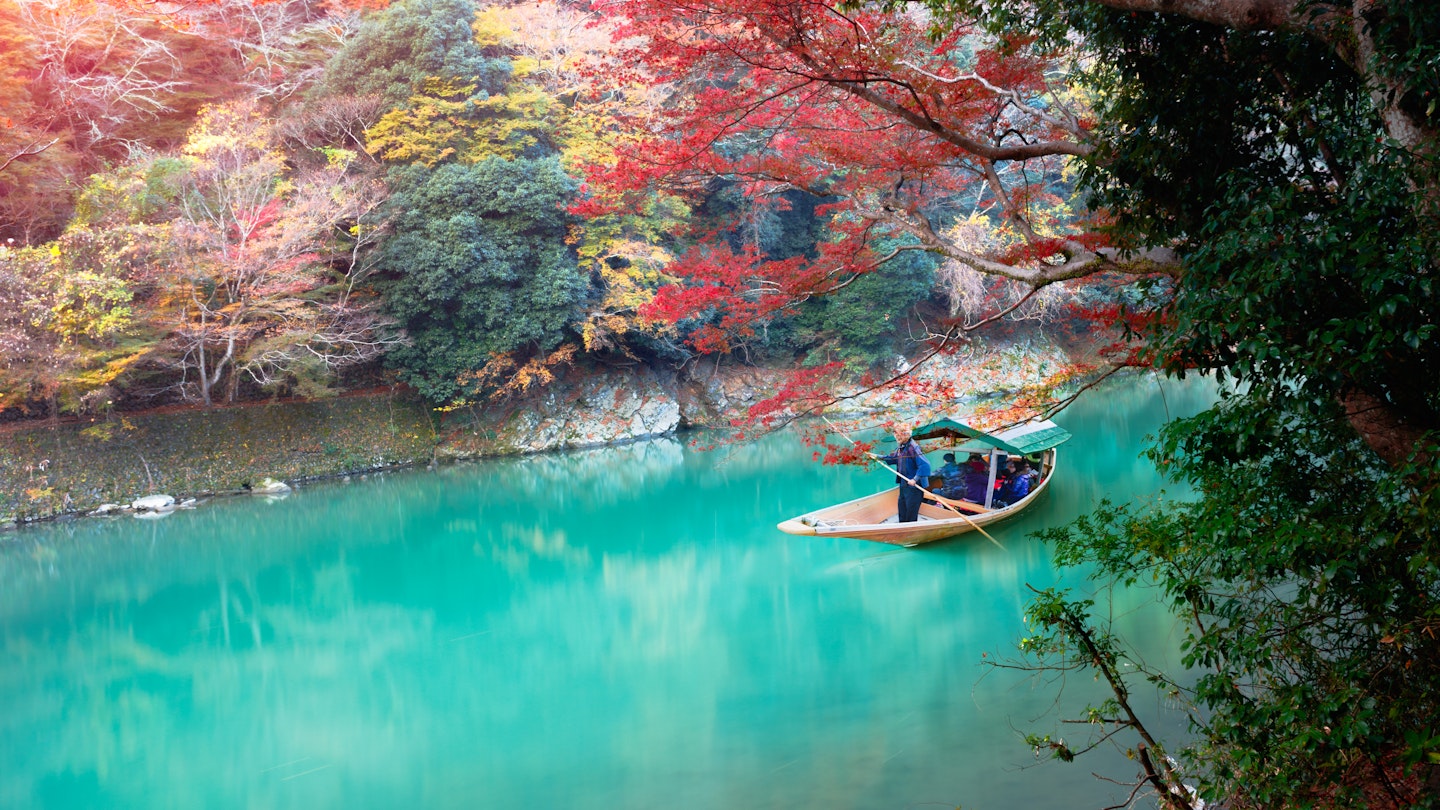 Boatman punting on Katsura River during an Autumn morning in Kyoto.
