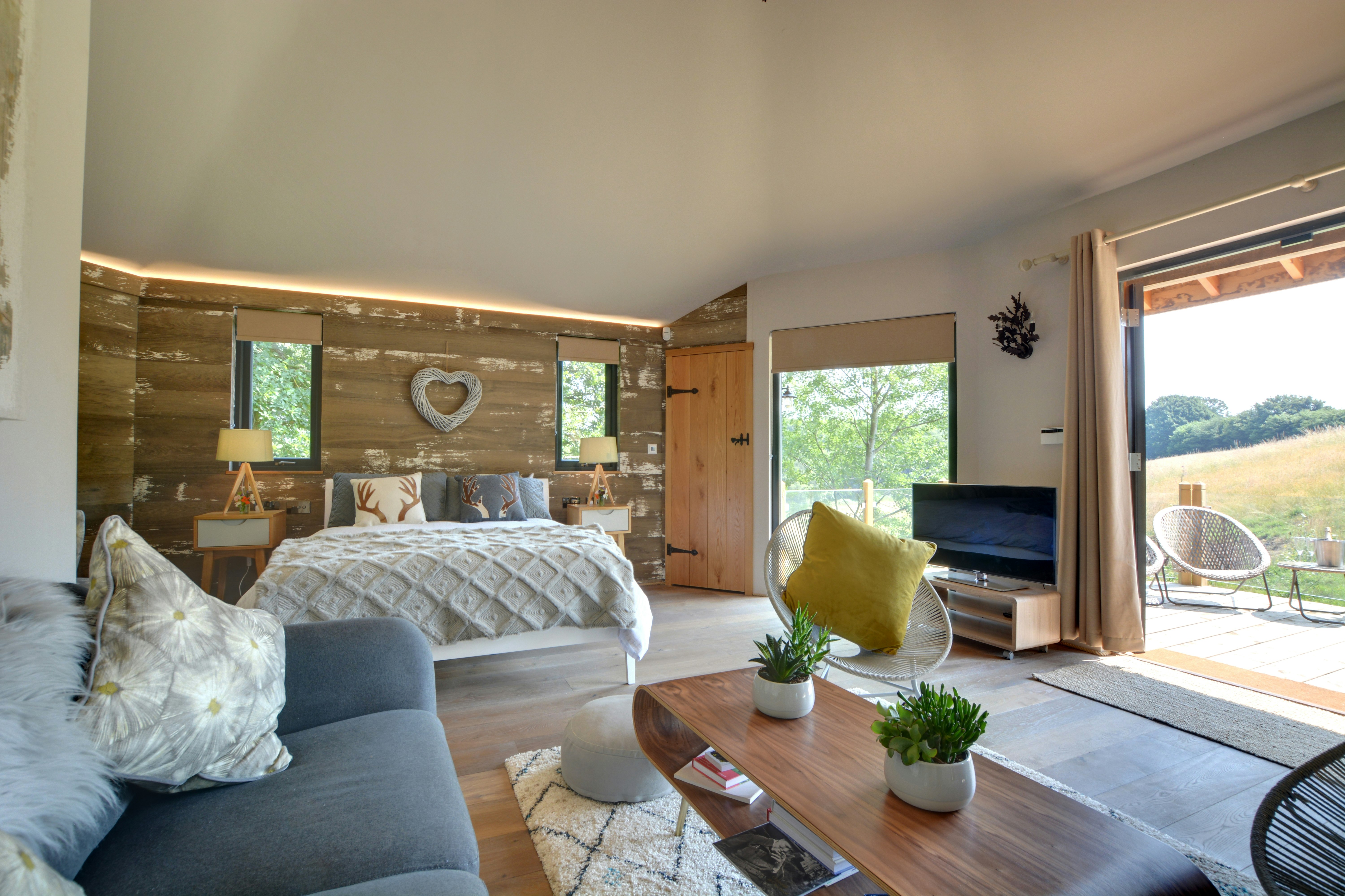 View of living room with and main bed in a tree house with rolling countryside outsided 