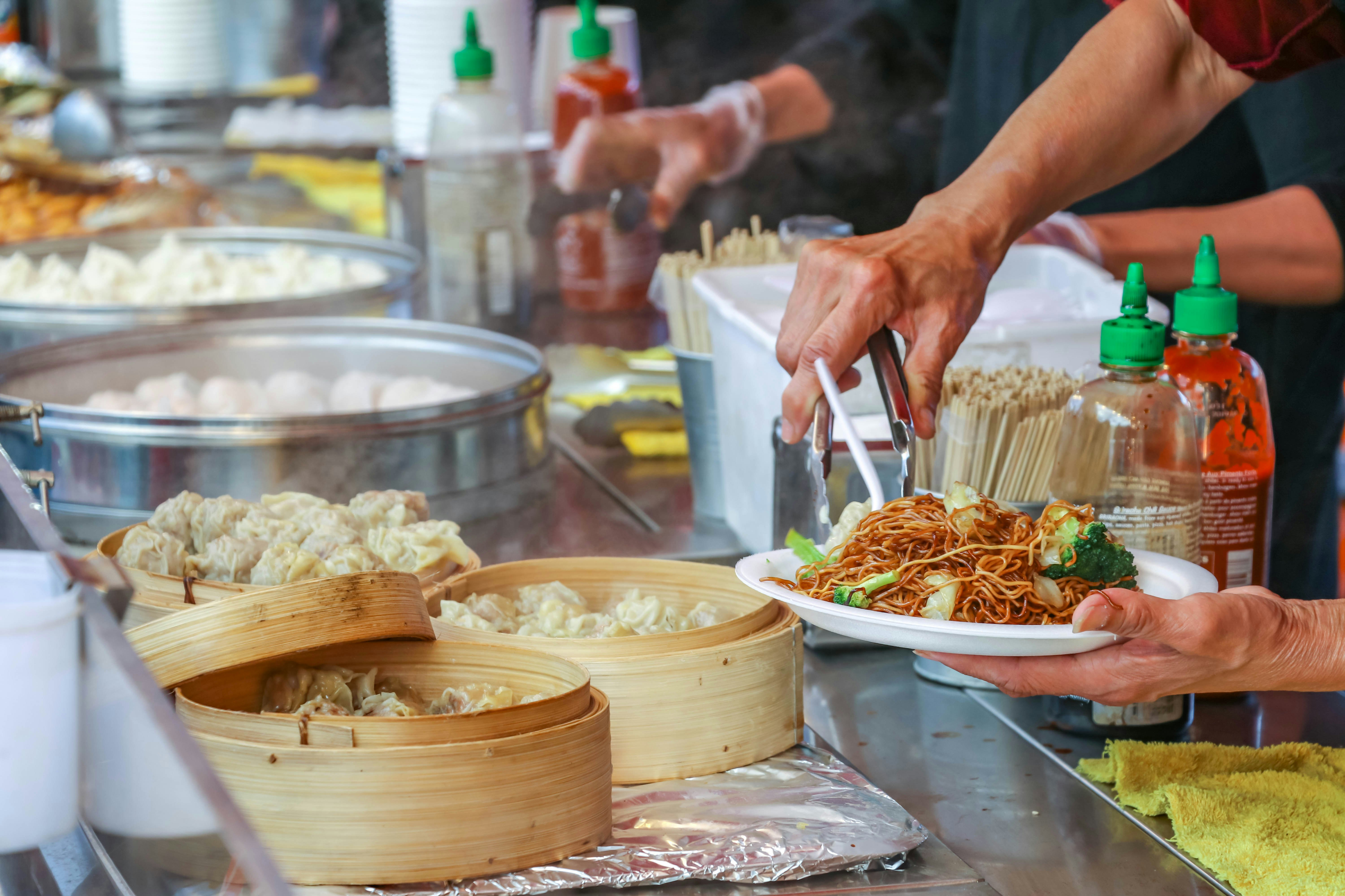 Richmond, BC, Canada - July 6, 2018: Piling food onto a plate. The night market is a popular destination on weekends in Vancouver. Food is the highlight of the market.