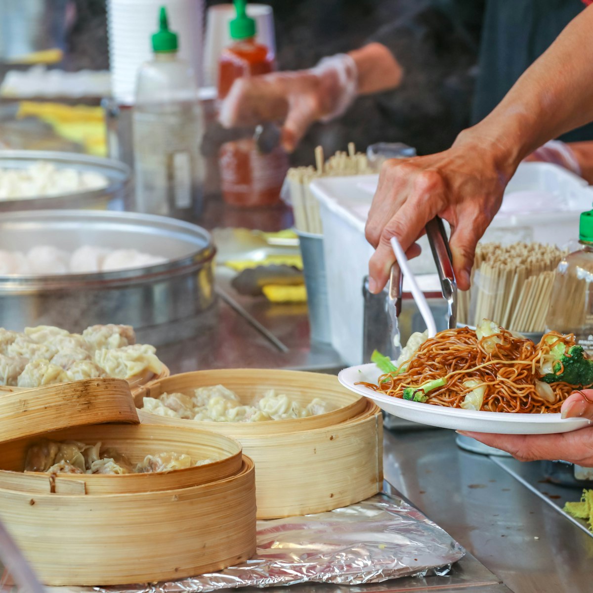 Richmond, BC, Canada - July 6, 2018:  Piling food onto a plate. The night market is a popular destination on weekends in Vancouver.   Food is the highlight of the market.