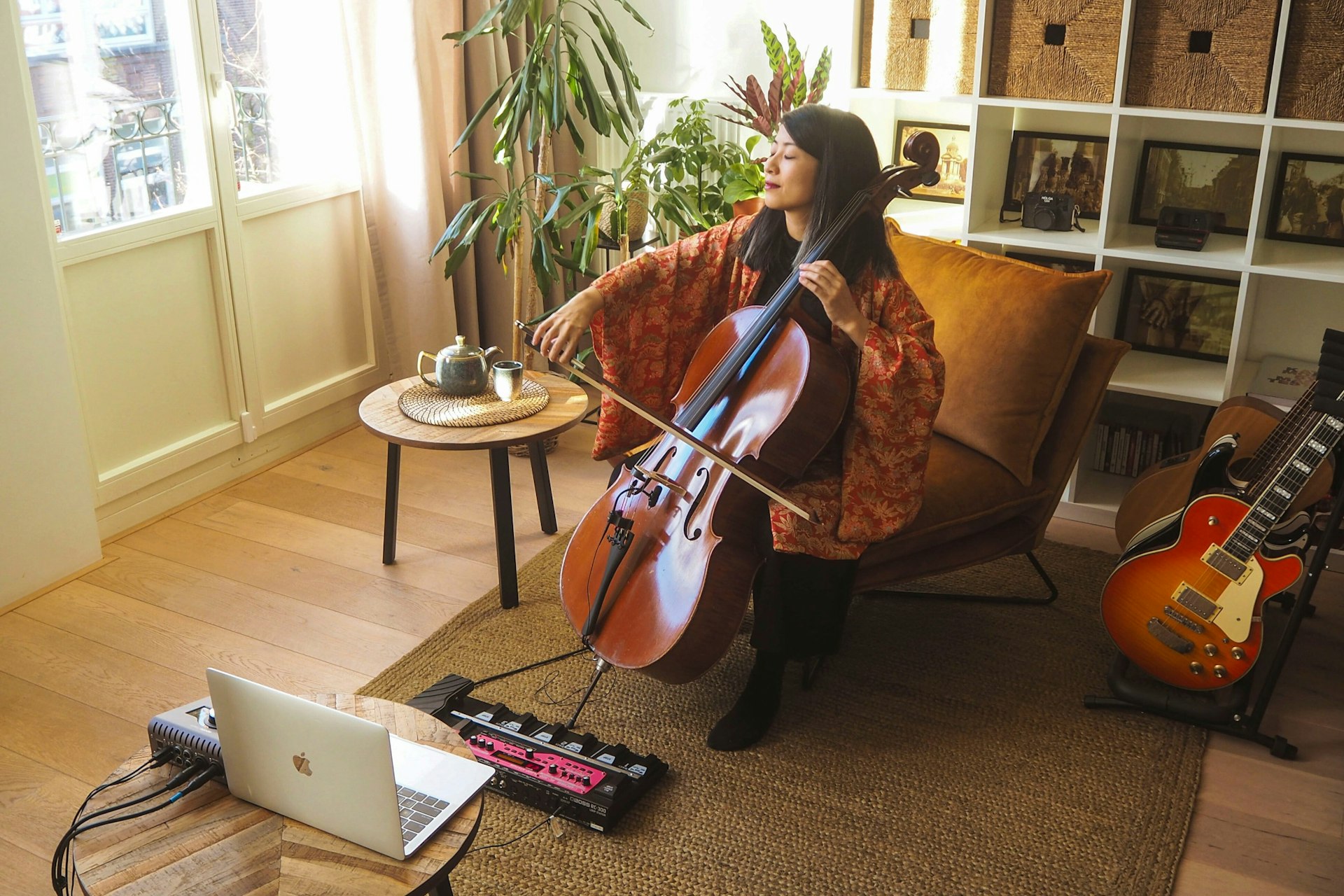 A woman playing a cello to an online audience via computer
