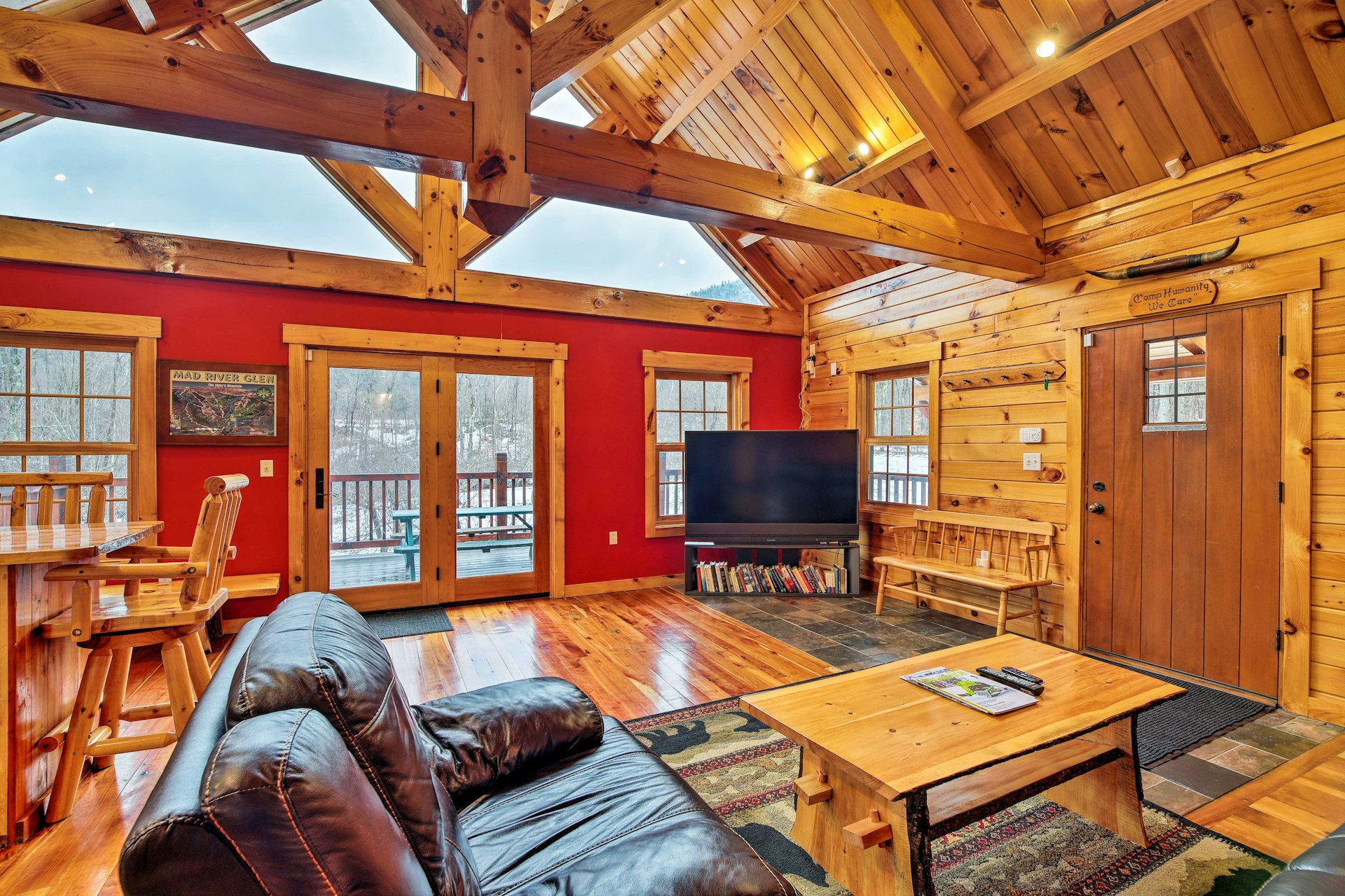 The living room at the Four-Season Mountain Retreat in Vermont, with wood paneling, leather couches, and red walls. 