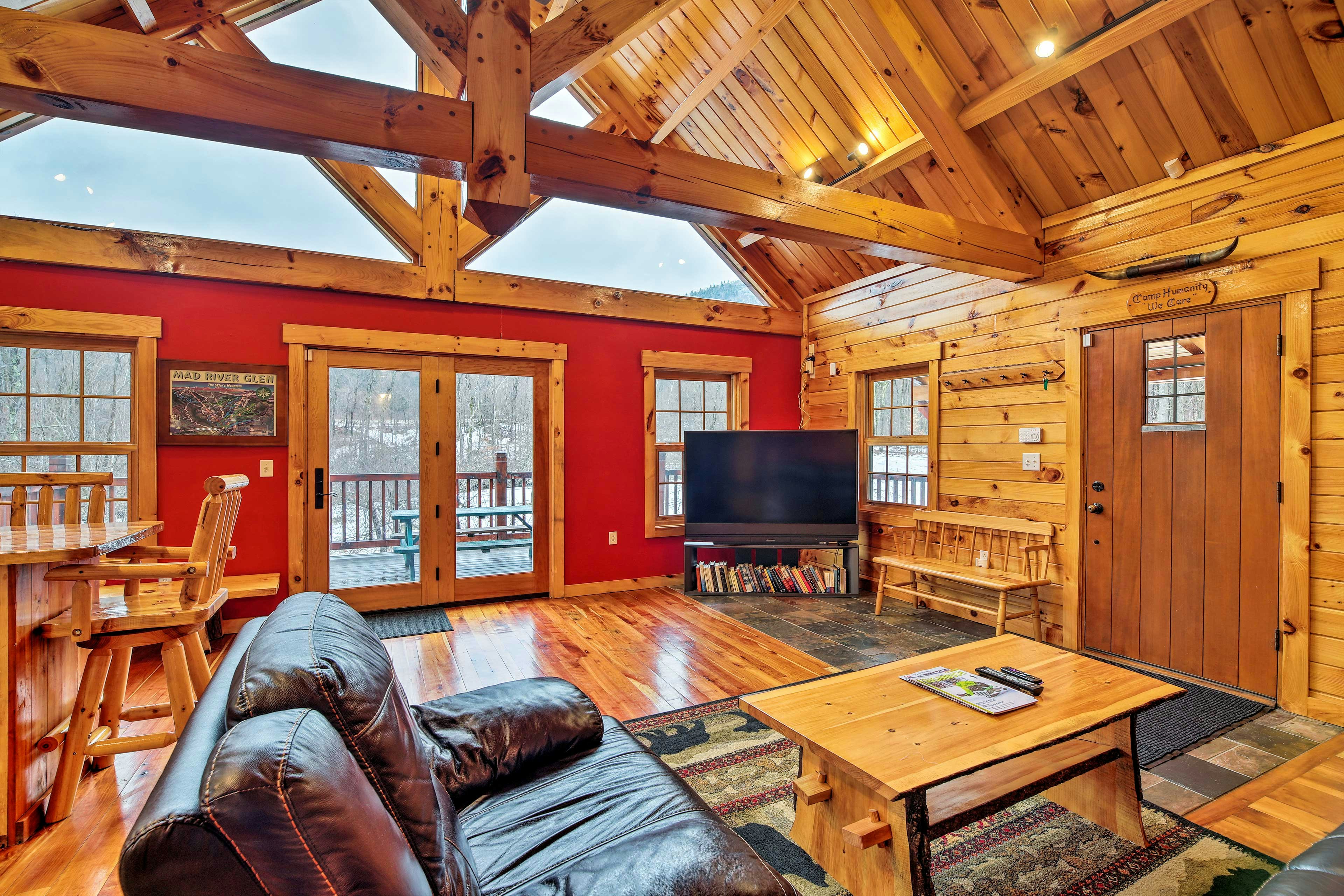 The living room at the Four-Season Mountain Retreat in Vermont, with wood paneling, leather couches, and red walls.