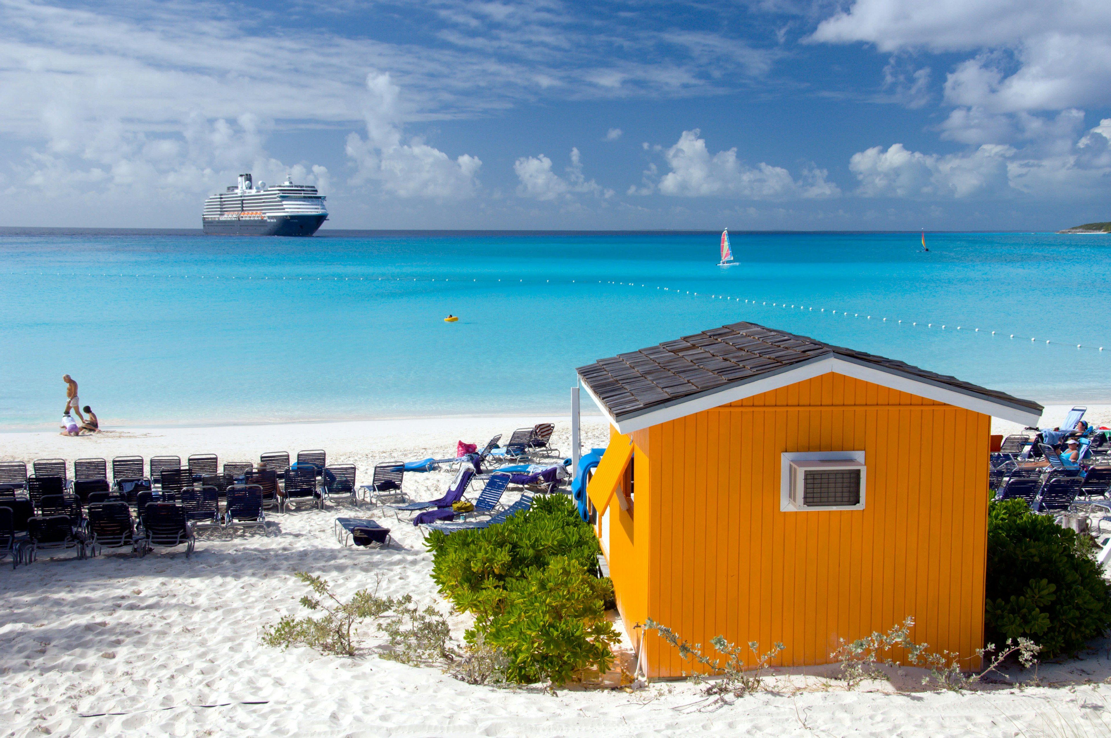 A colourful beach cabana with the Holland America cruise ship Westerdam in background at Half Moon Cay, Bahamas, Caribbean.