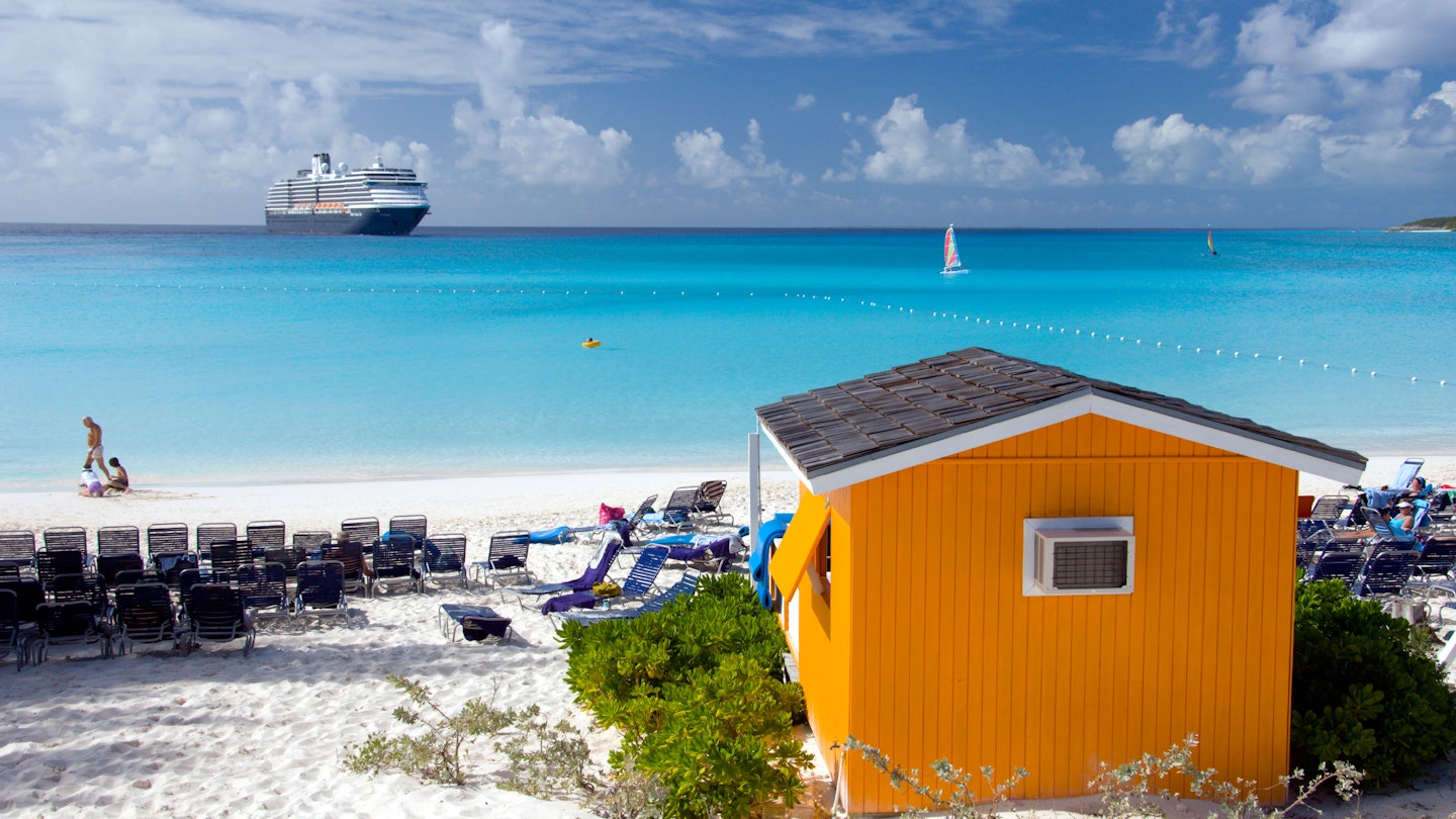 A colourful beach cabana with the Holland America cruise ship Westerdam in background at Half Moon Cay, Bahamas, Caribbean.