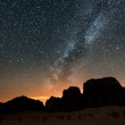 Milky Way above silhouetted cliffs at Wadi Rum desert.