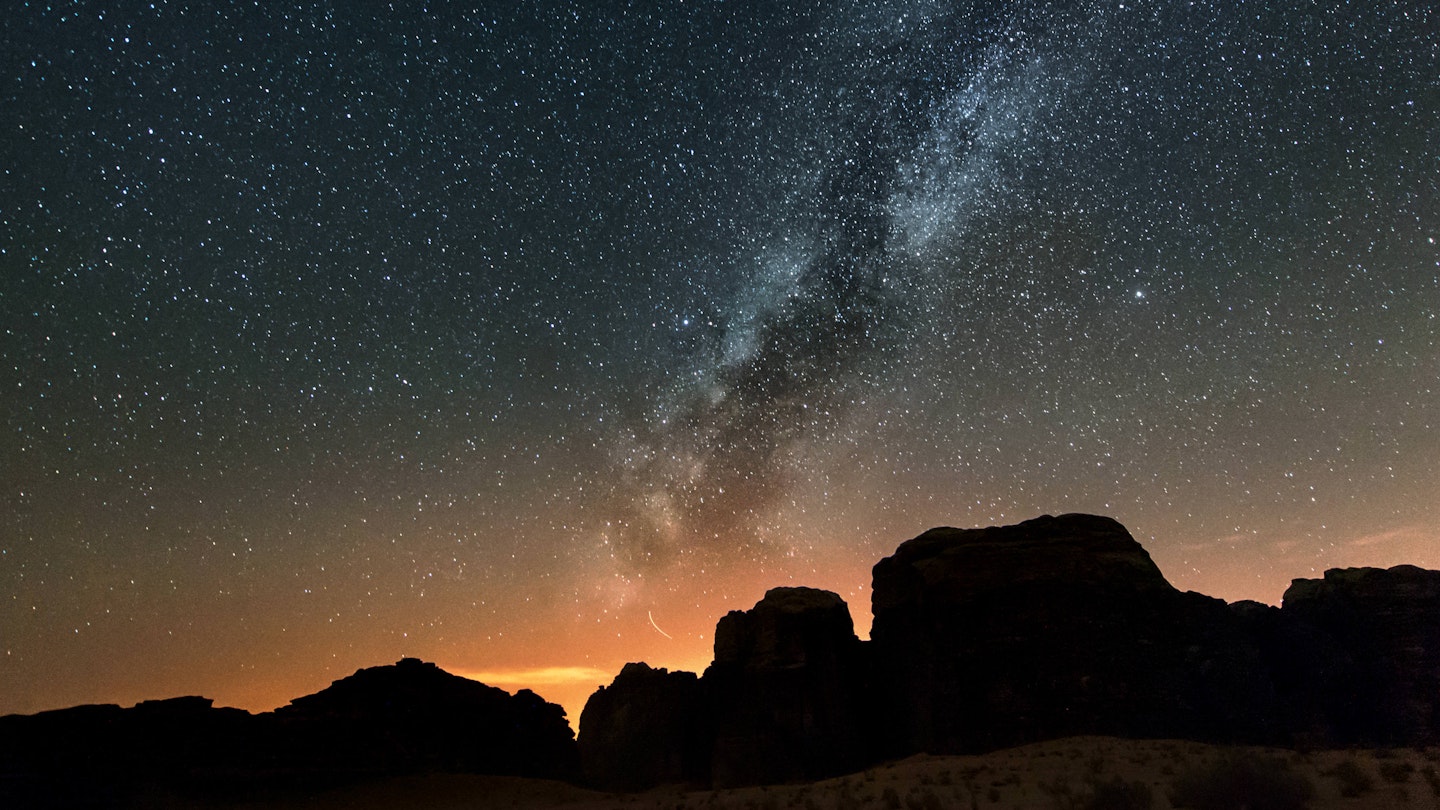 Milky Way above silhouetted cliffs at Wadi Rum desert.