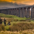 Photographers capturing the Ribblehead Viaduct on the Settle-Carlisle railway in low light.