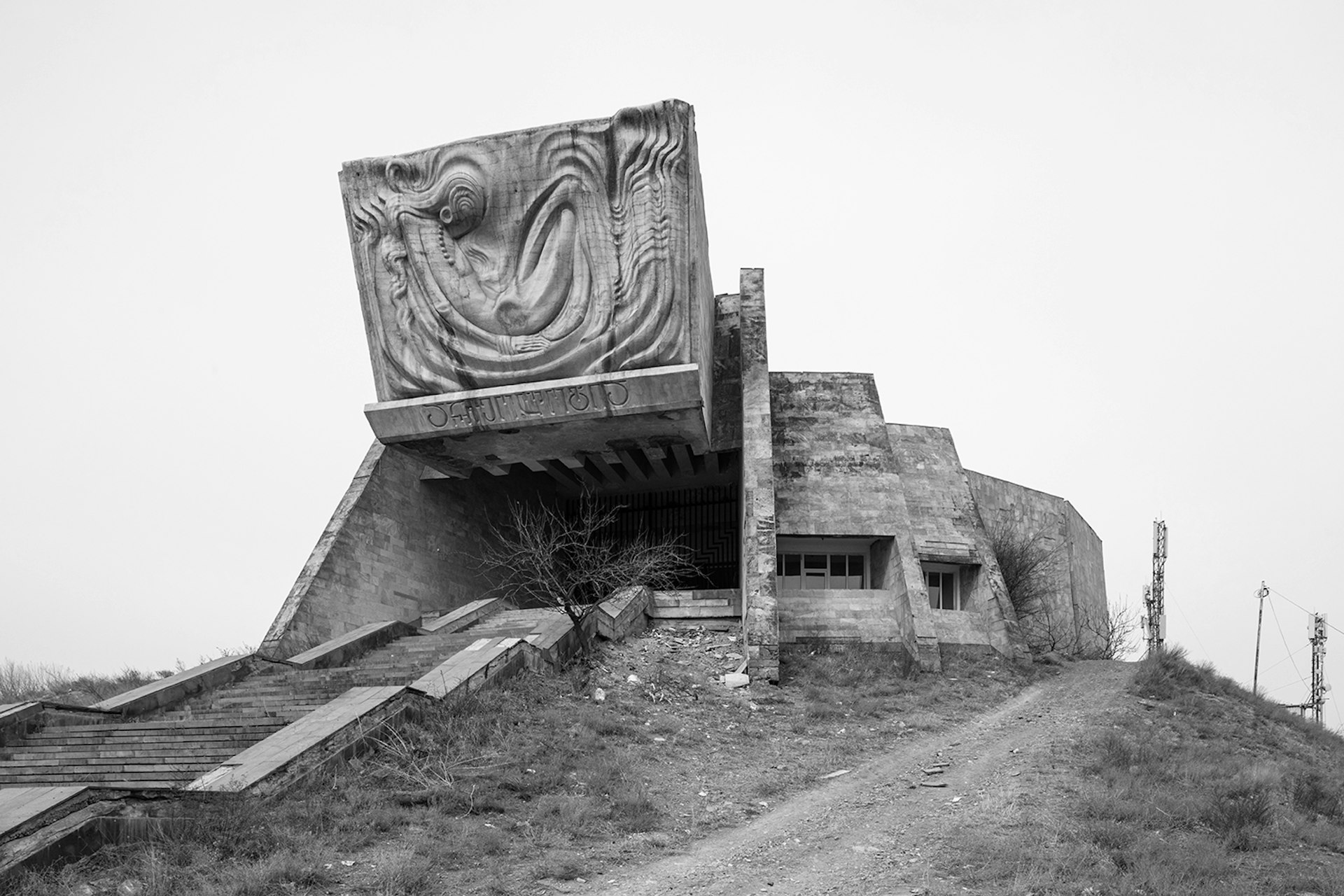 Archaeological Museum, like a concrete bunker forming the top of a hillside, has a large decorative slab of concrete above the entrance, open like a giant flap