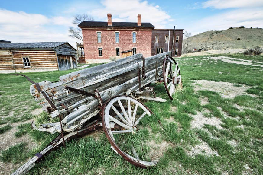 A discarded and decaying wagon (still holding planks of wood) sits on a patch of land in Bannack ghost town, Montana