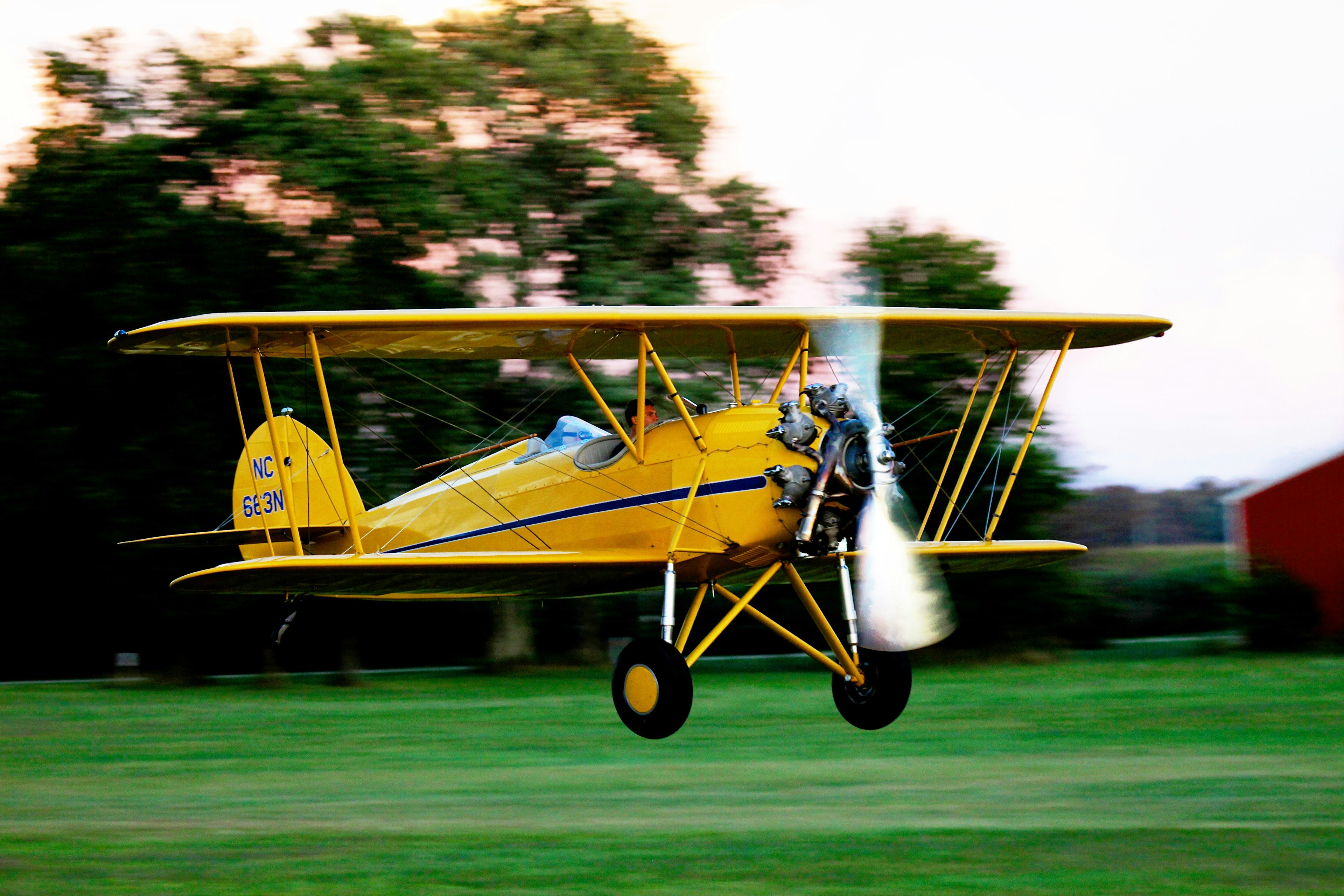 A yellow bi plane takes off