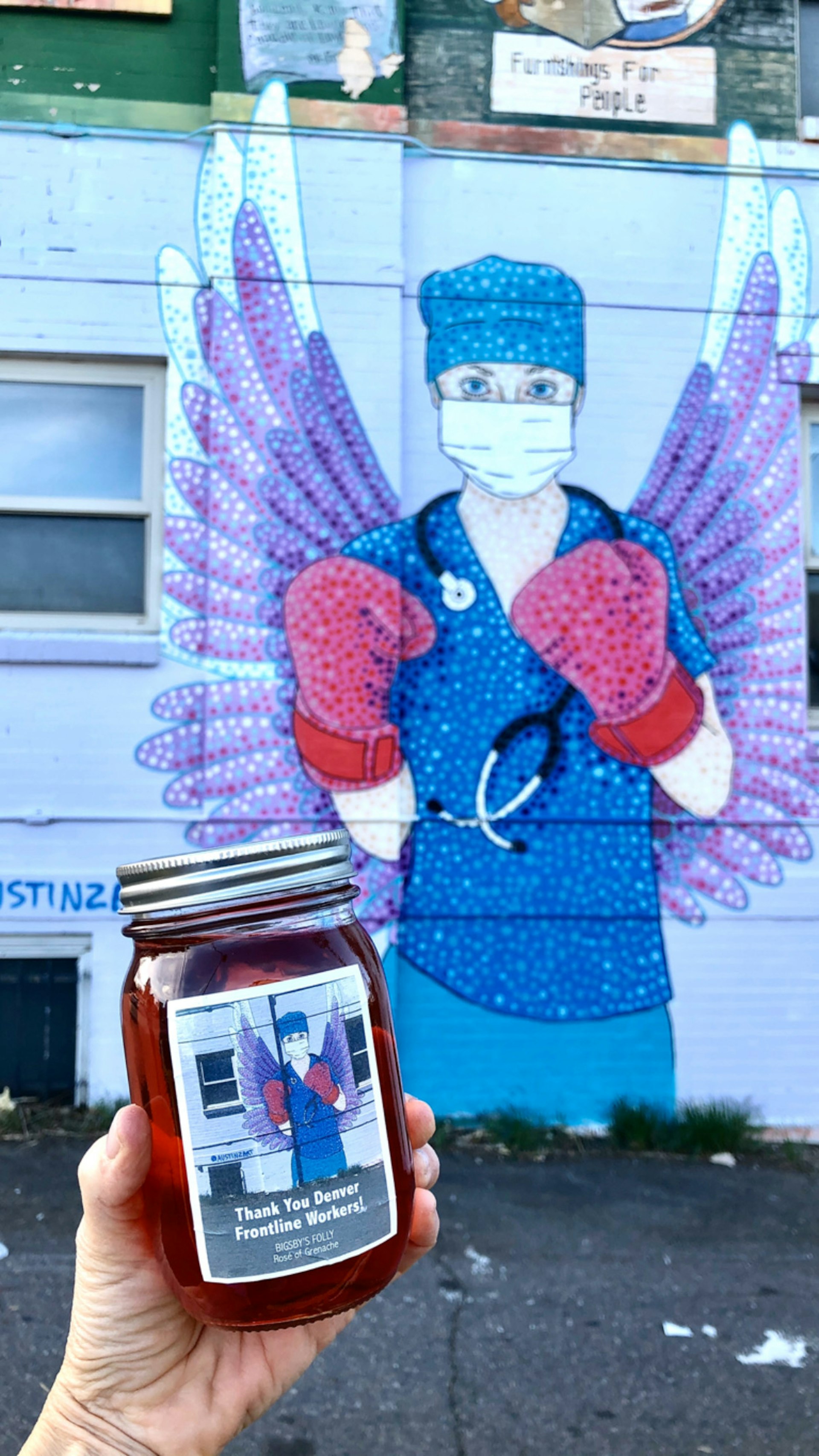 Mural of a nurse with wings and boxing gloves in the background with a pint of wine in the foreground
