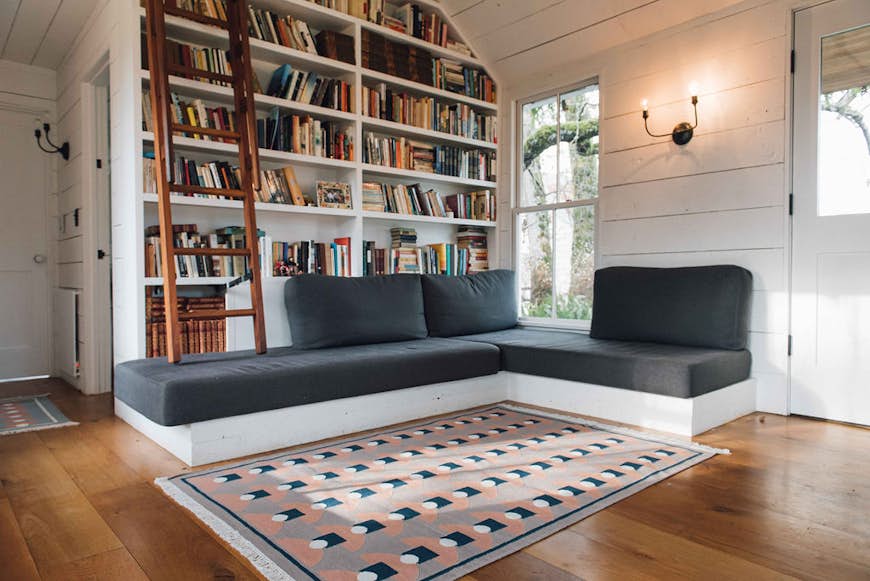 Bloom & Give Tushar dhurrie matta framför en soffa och bokhyllor