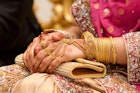 Muslim brides hands decorated with henna and gold jewellery.