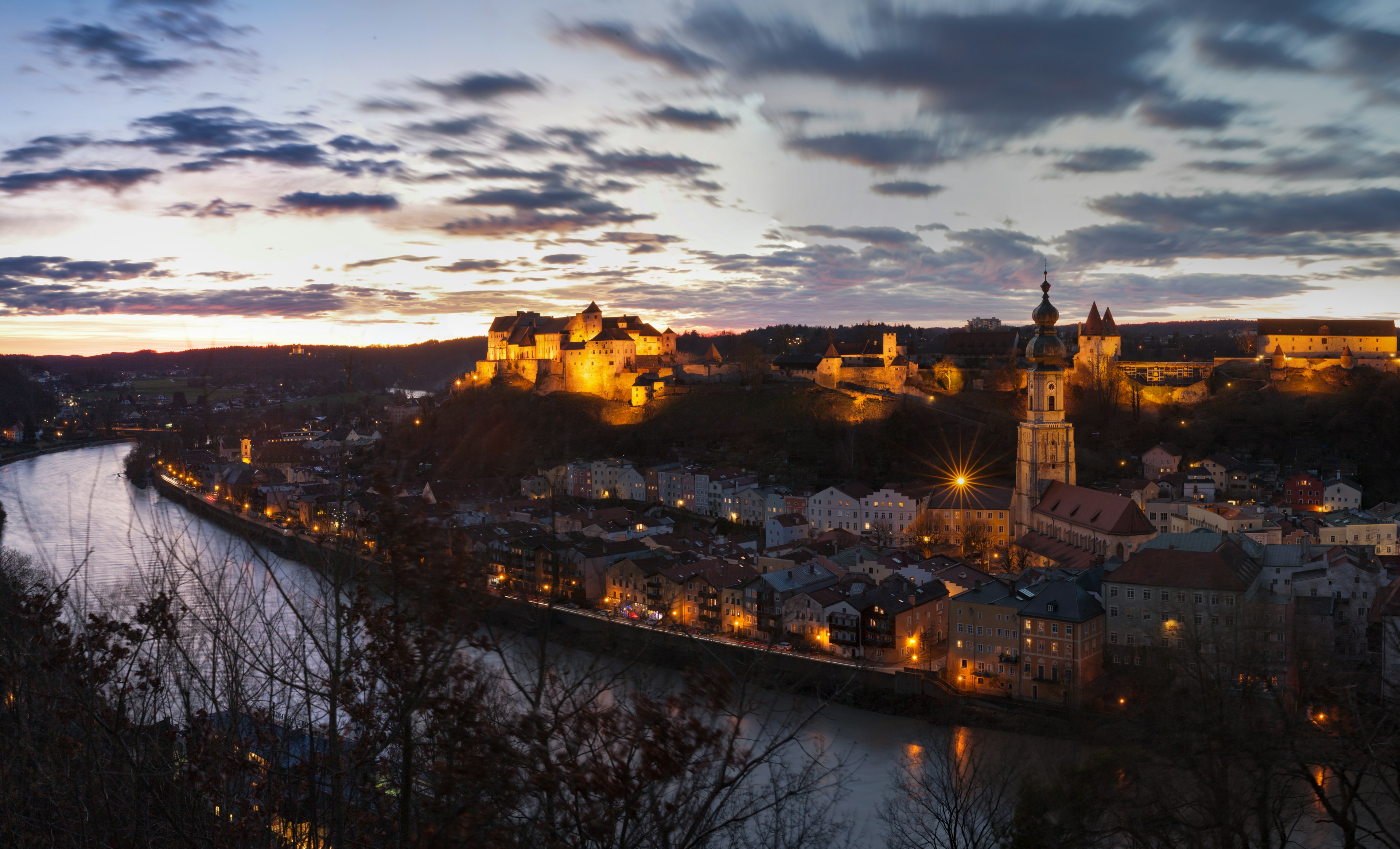 A castle above a river lit up at dusk