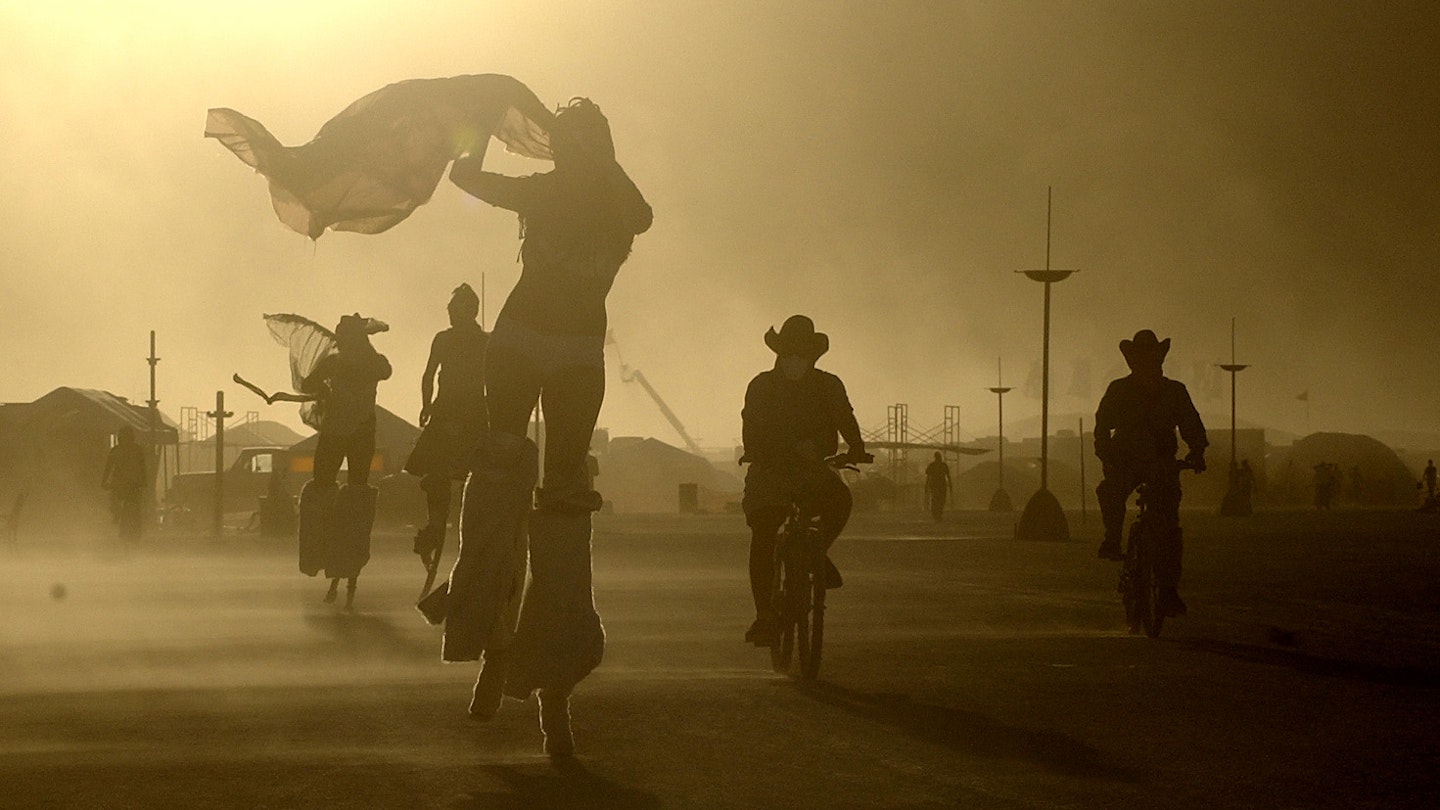 BURNING MAN -- 08/28/05 -- BLACK ROCK DESERT, NV -- An day-long windstorm whips sand as fine as talcum powder at Burning Man as participants take evening bike rides and strolls on stilts. About 35,000 are camped out on the desert for the week-long party and arts festival, which ends Monday. -- DIGITAL IMAGE -- JIM RANKIN/THE TORONTO STAR (Photo by Jim Rankin/Toronto Star via Getty Images)