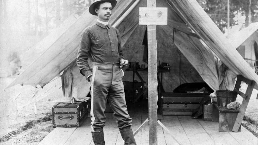 Buffalo soldier. T.R. Clarke, 8th US Volunteer Infantry, standing in front of tent, during the Spanish-American War. ca. 1898
